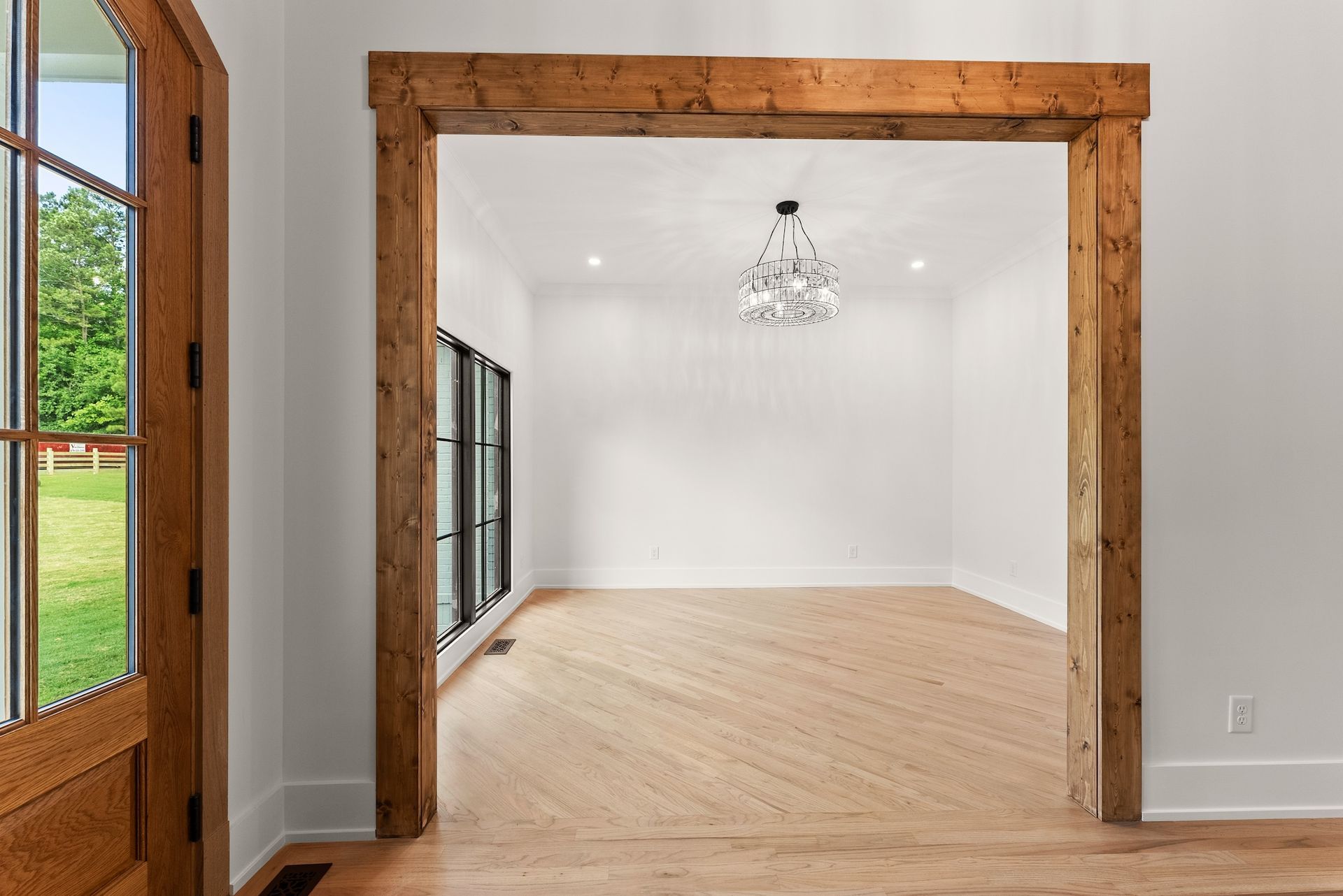 An empty room with wooden beams and a chandelier hanging from the ceiling.