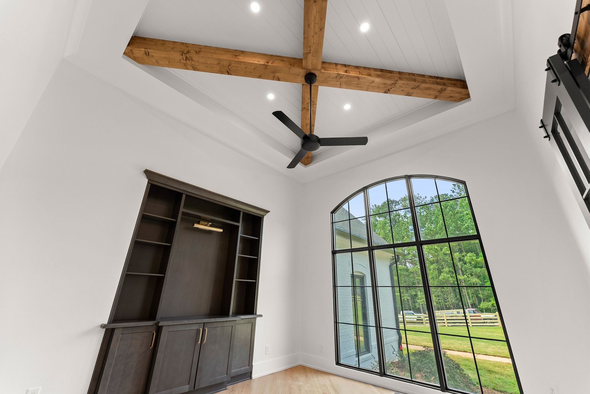 A living room with a ceiling fan and a large window.