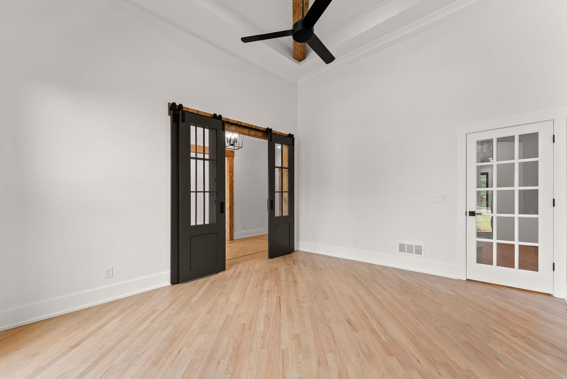 An empty room with wooden floors and a ceiling fan.