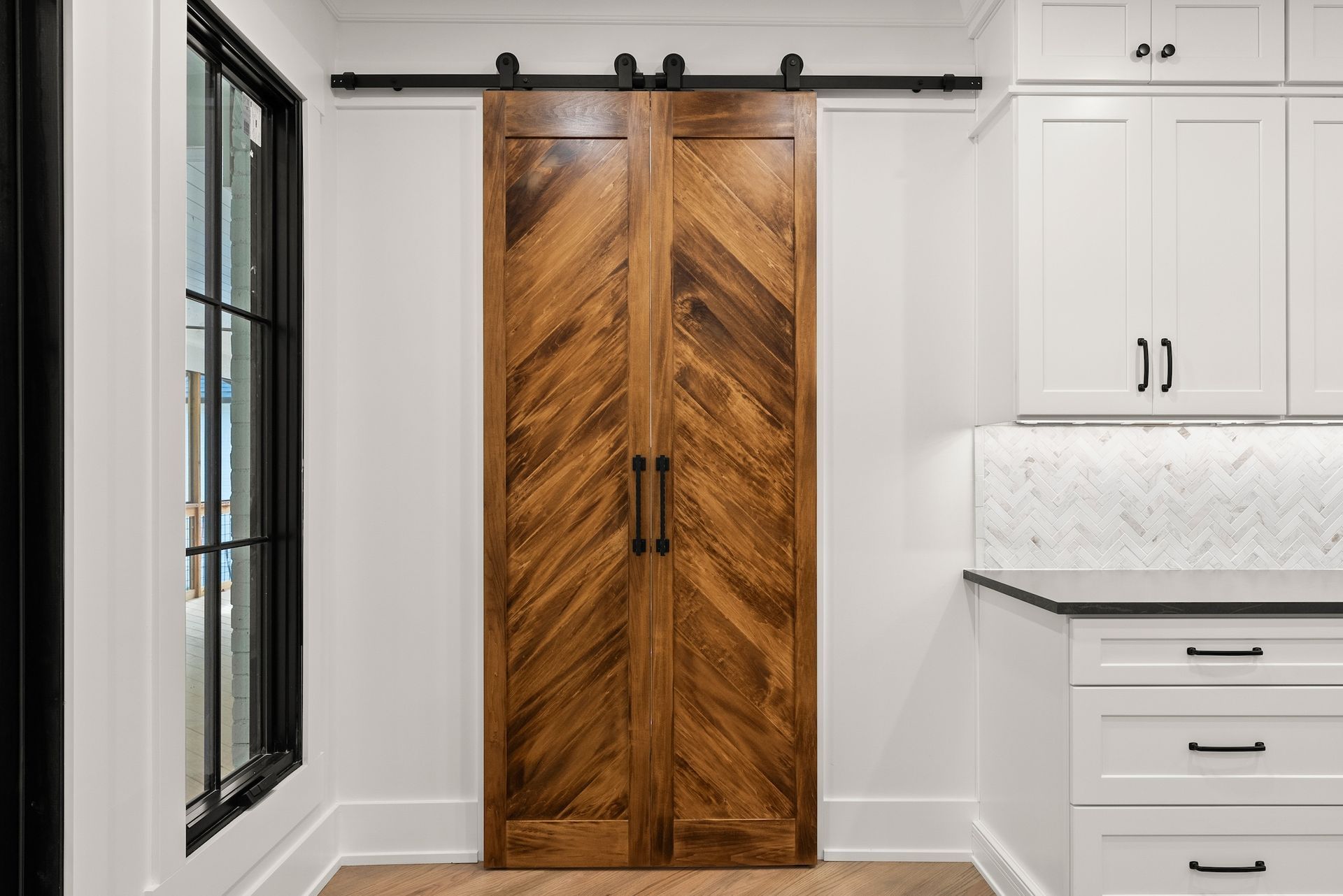 A kitchen with a sliding barn door and white cabinets.