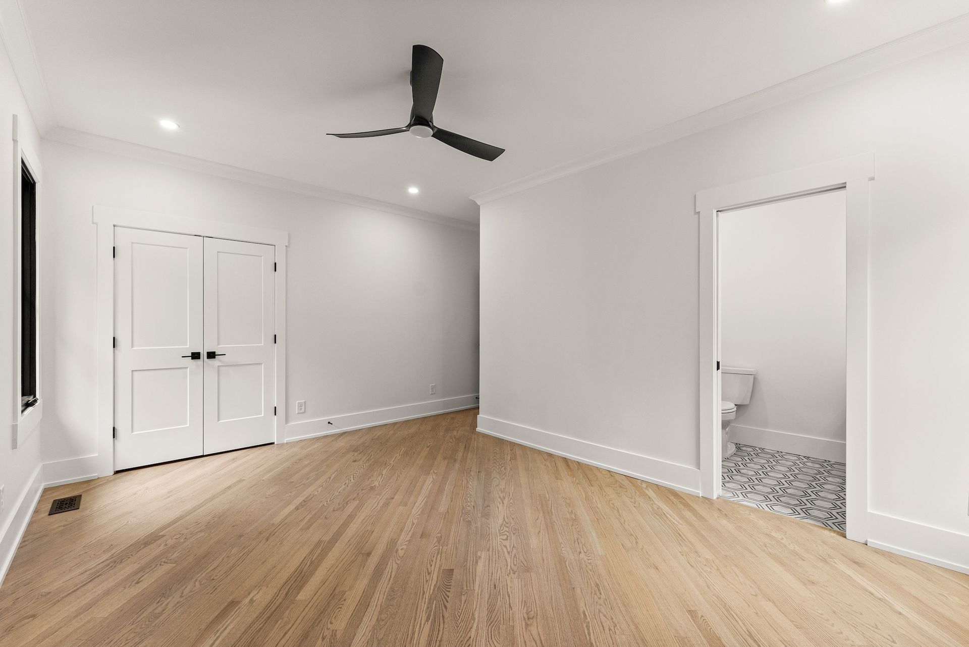 An empty room with hardwood floors and a ceiling fan.