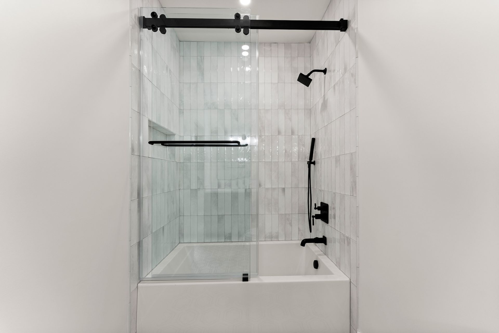 A bathroom with a bathtub and a shower with a sliding glass door.