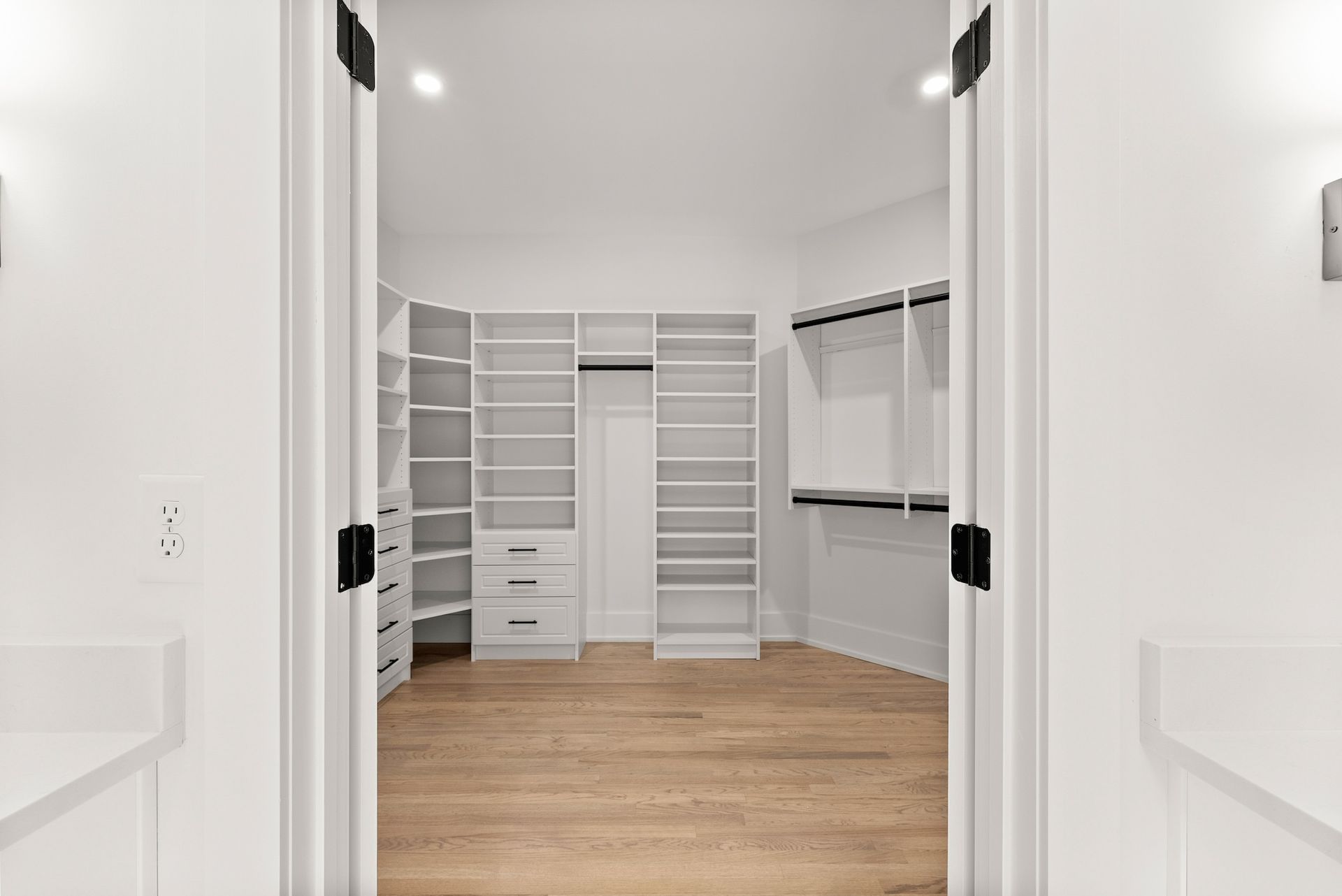 A walk in closet with lots of shelves and drawers in a house.