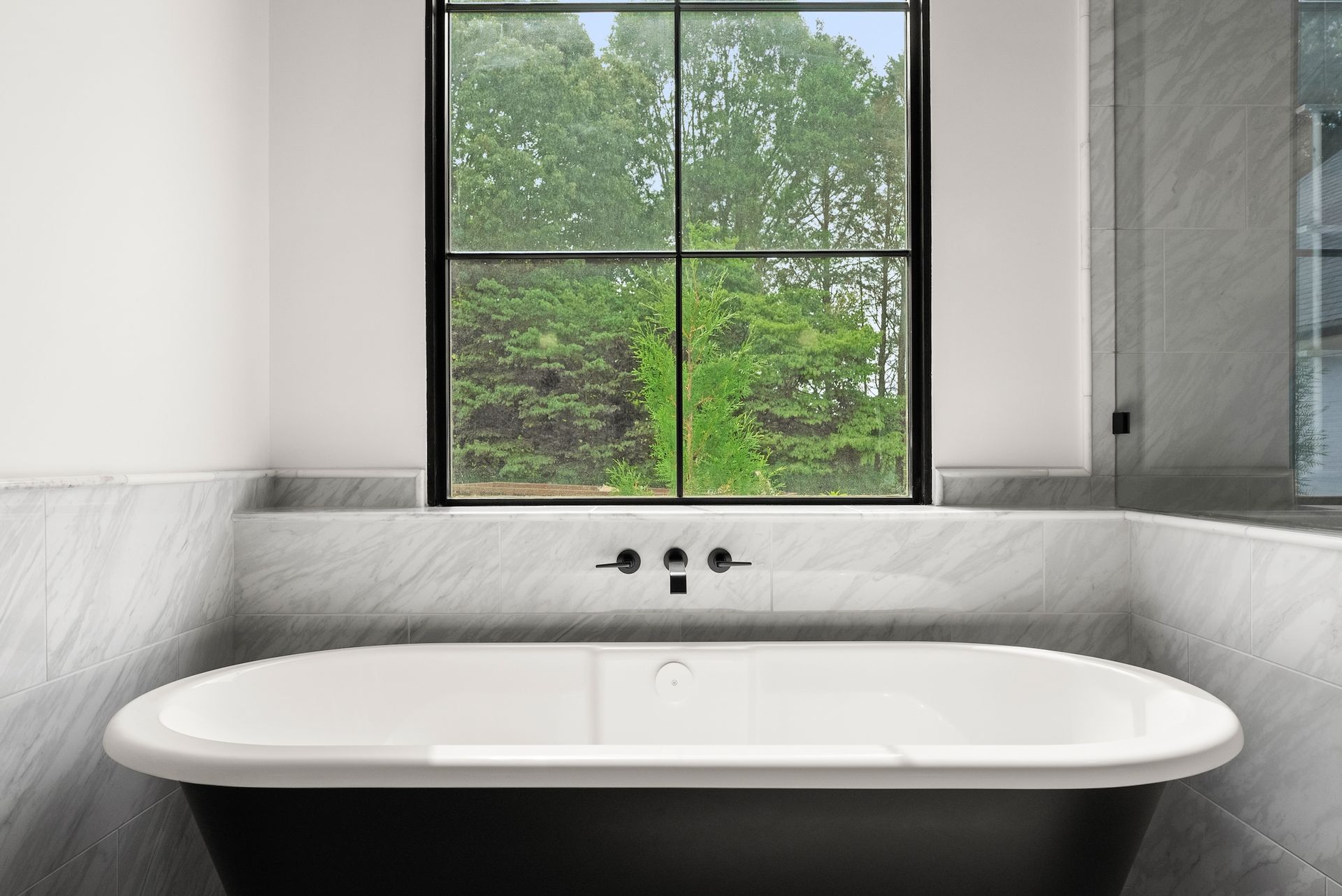 A bathroom with a bathtub and a window with trees in the background.