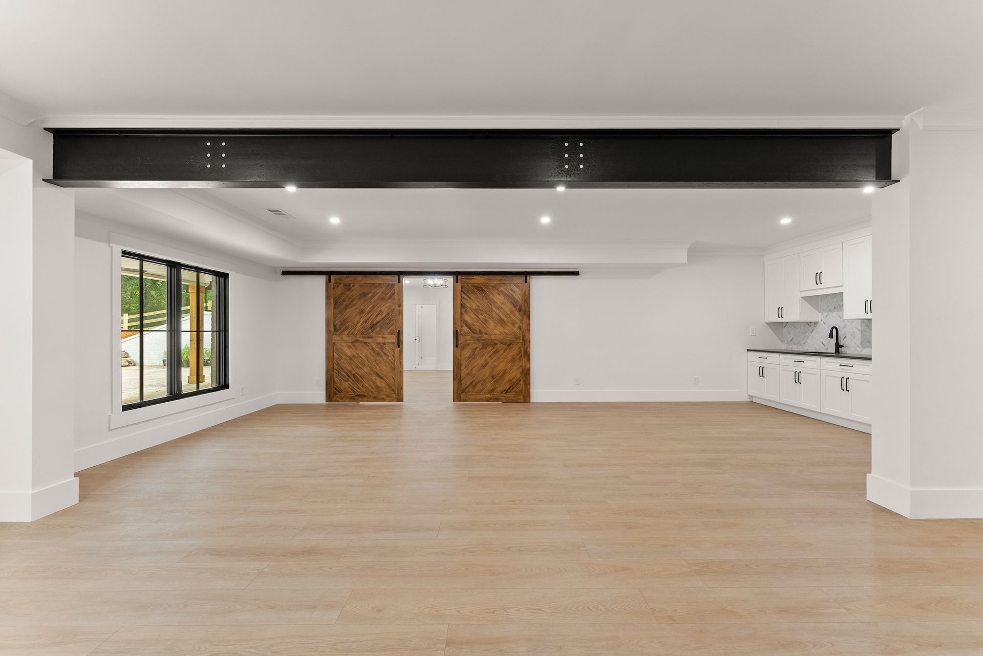 A large empty room with wooden floors and sliding barn doors.