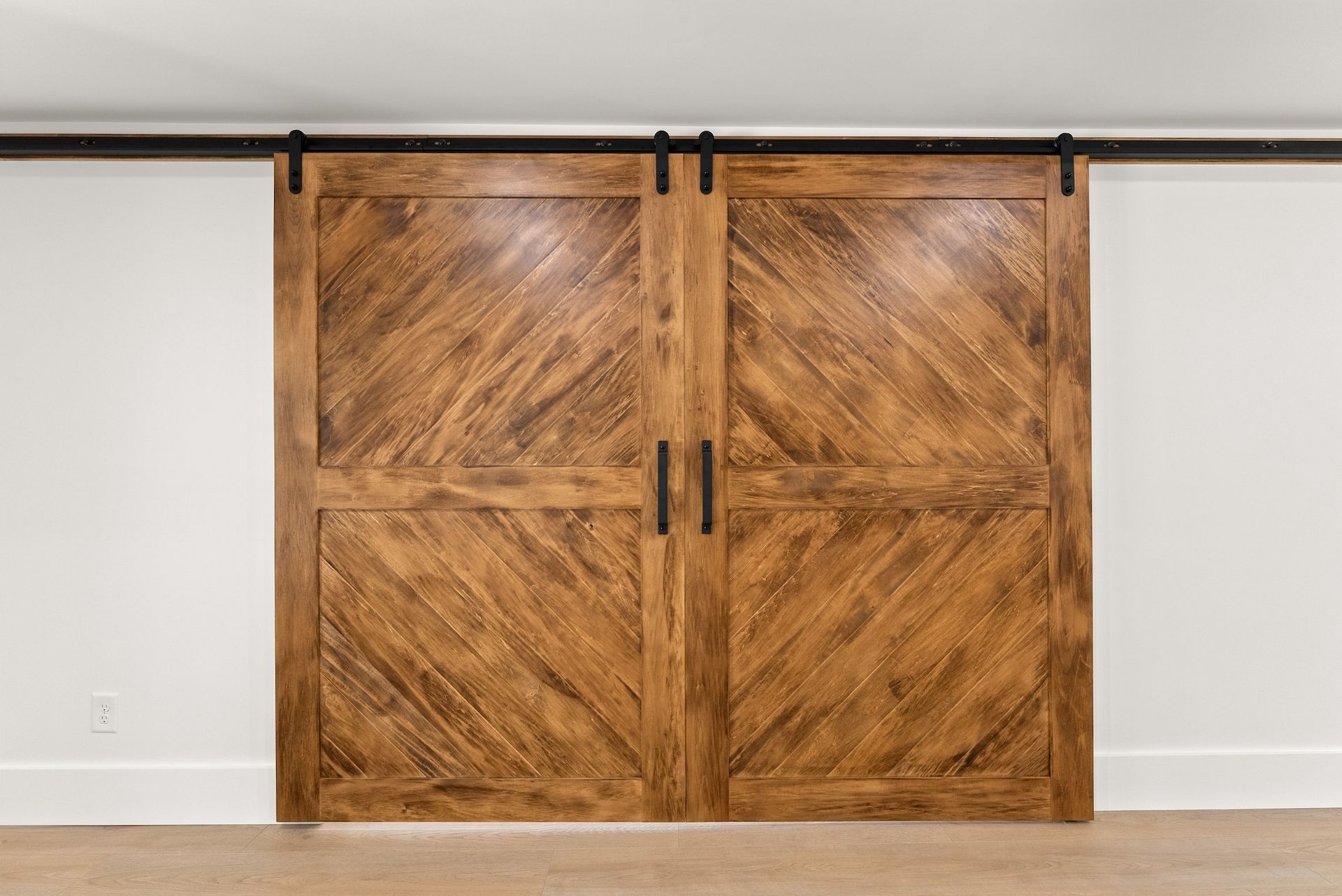 A pair of wooden sliding barn doors on a white wall.