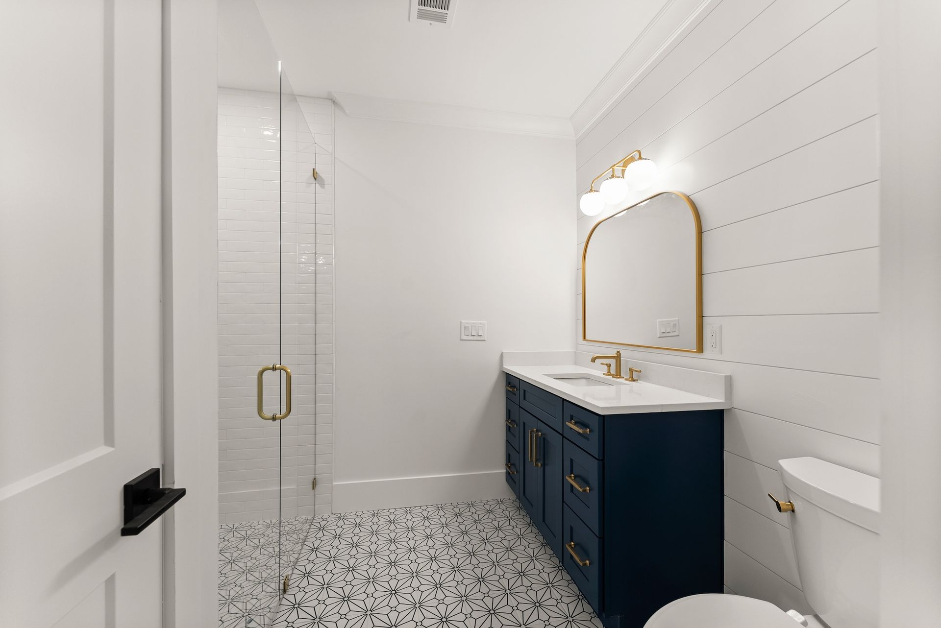 A bathroom with two sinks , a toilet , and a walk in shower.