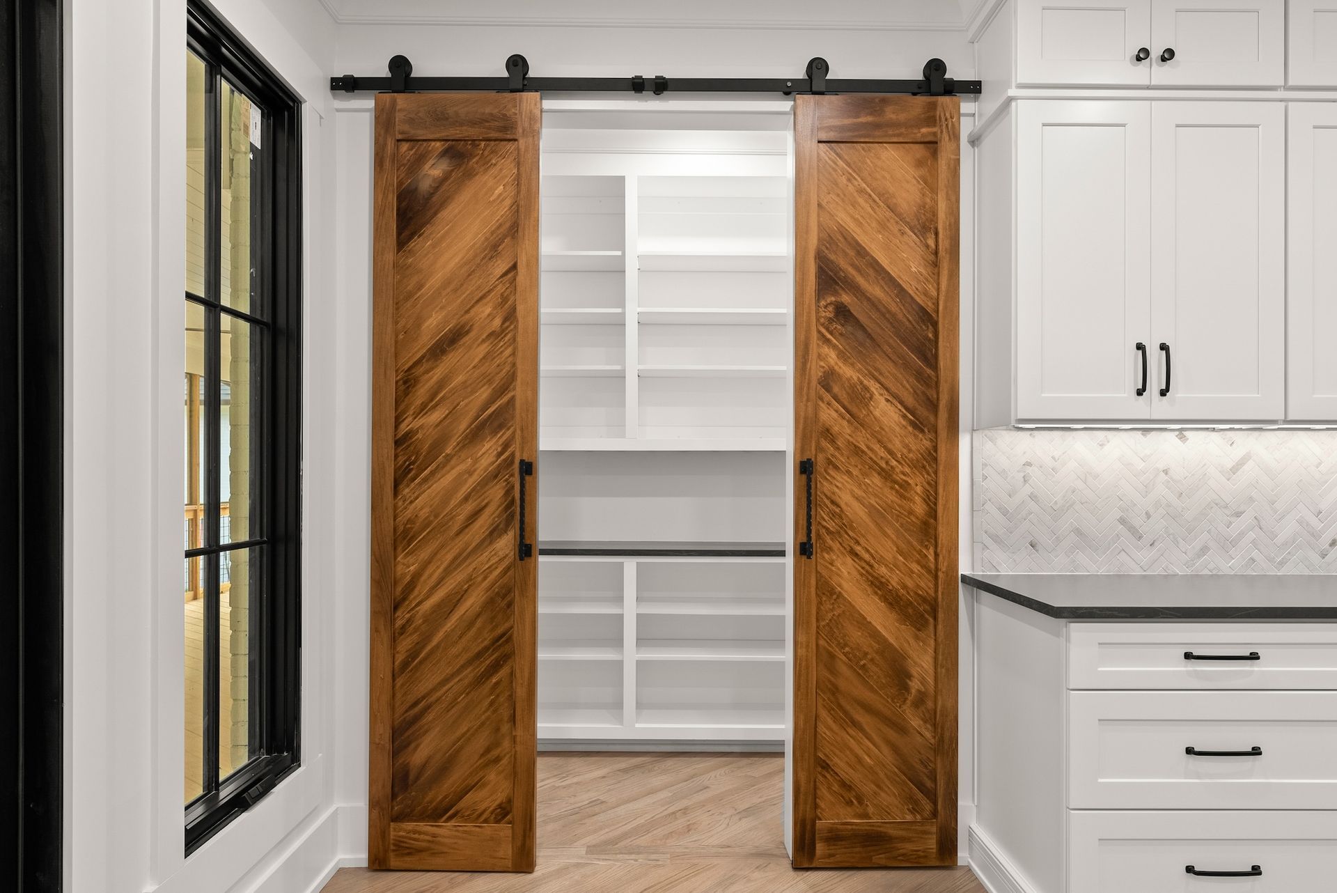A kitchen with sliding barn doors and white cabinets.