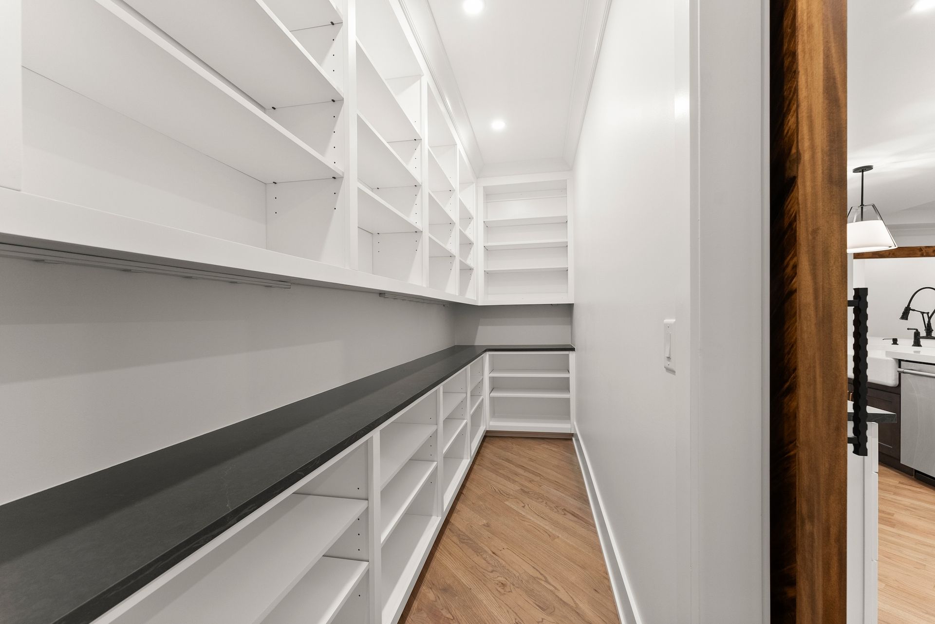 A long hallway with lots of shelves and a wooden floor.