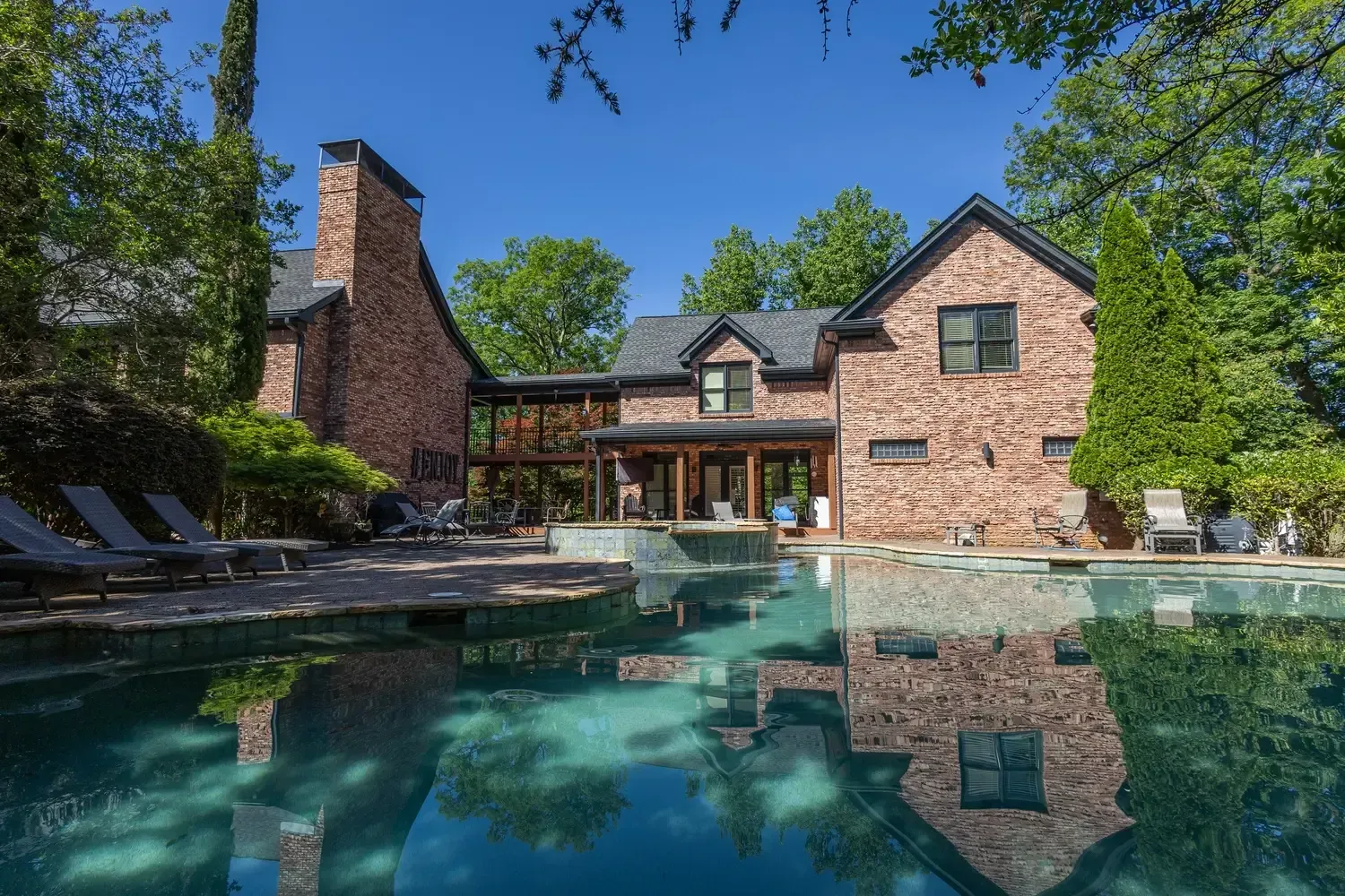 A large brick house with a large swimming pool in front of it