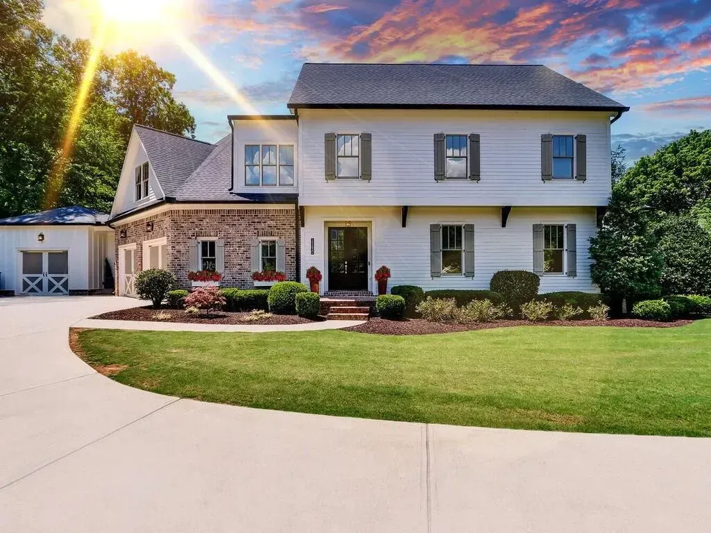 A large white house with a lush green lawn and a driveway.