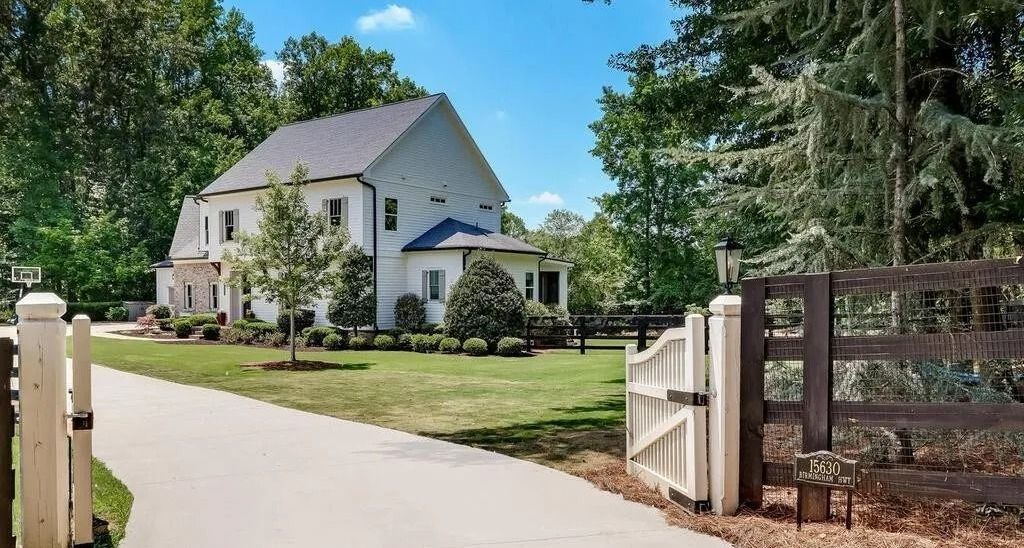 A large white house with a fence in front of it is for sale.