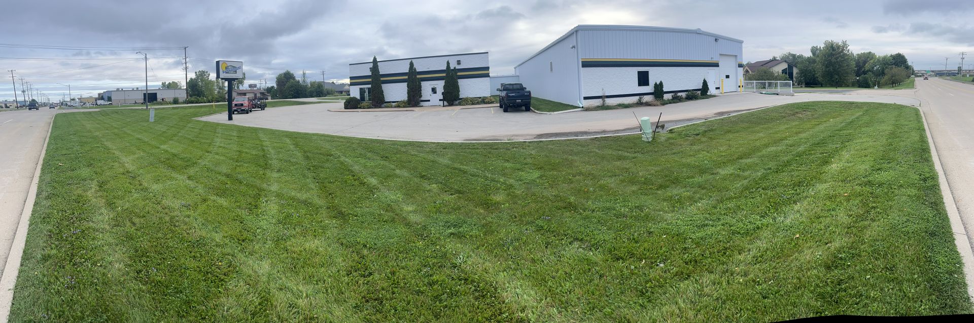 A building with gas pumps and a large lawn under an overcast sky.