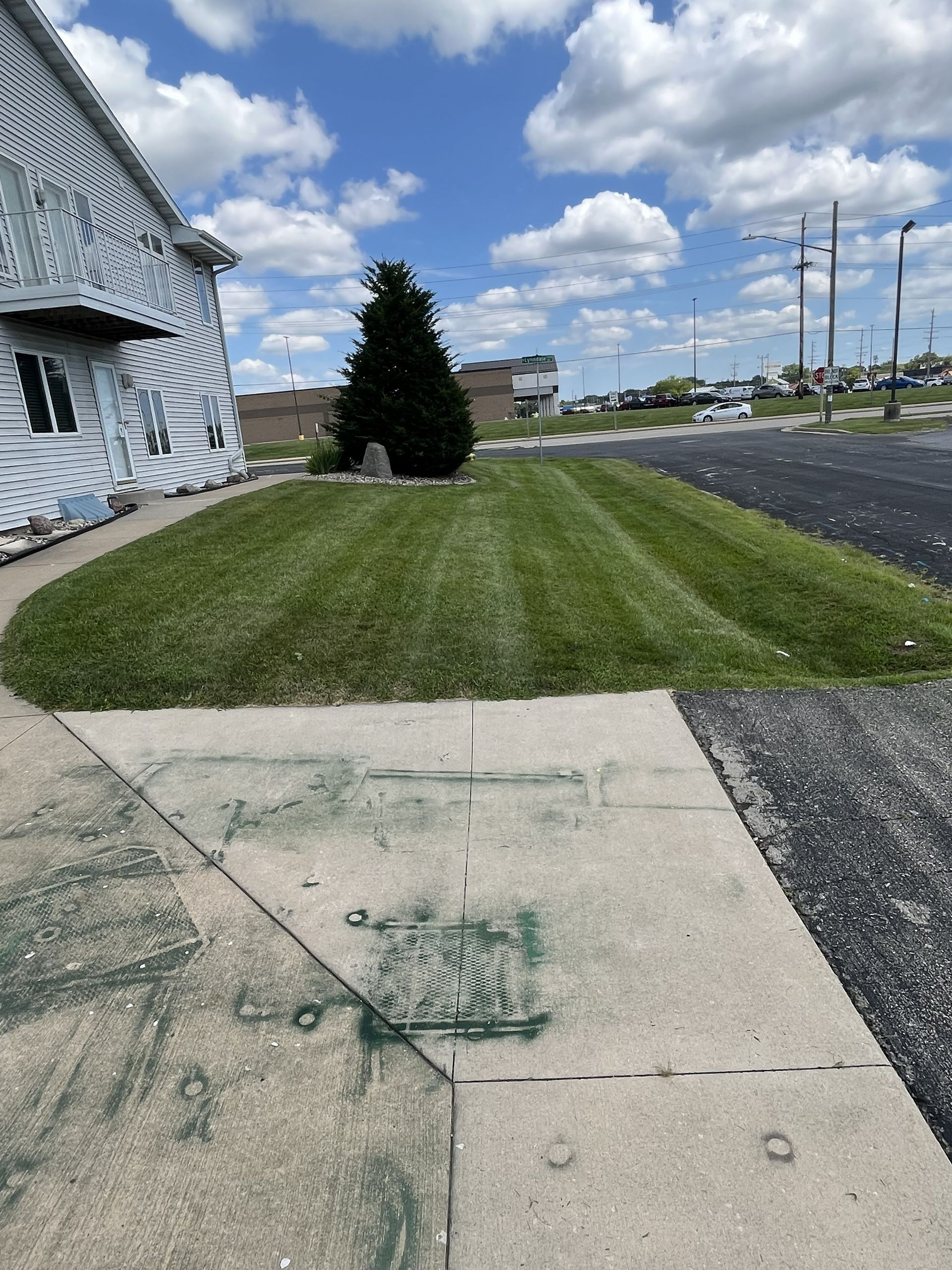 Lawn freshly mowed in front of a building on a sunny day with a blue sky.