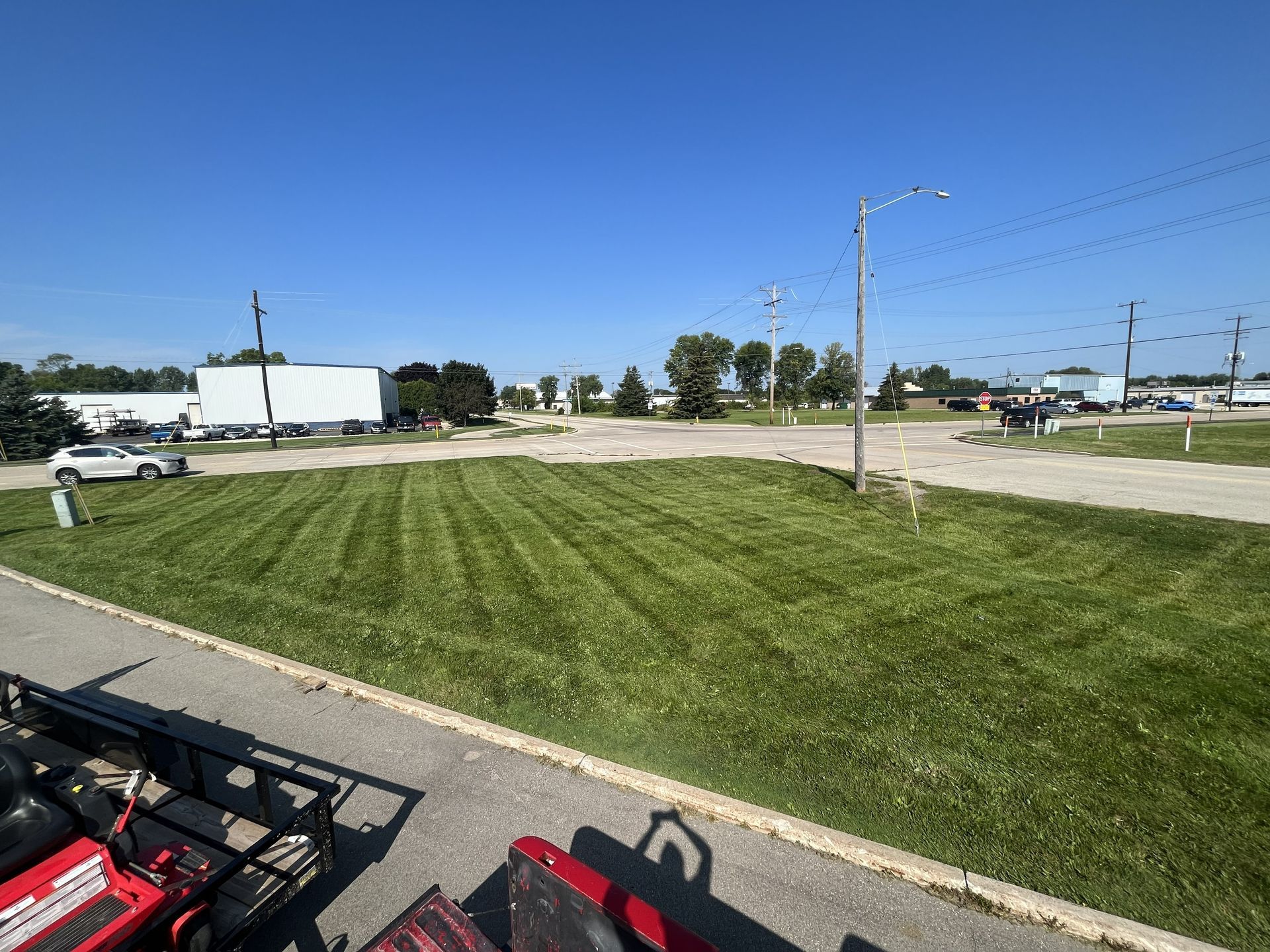Lawn recently mowed in an open area, buildings in background, blue sky.