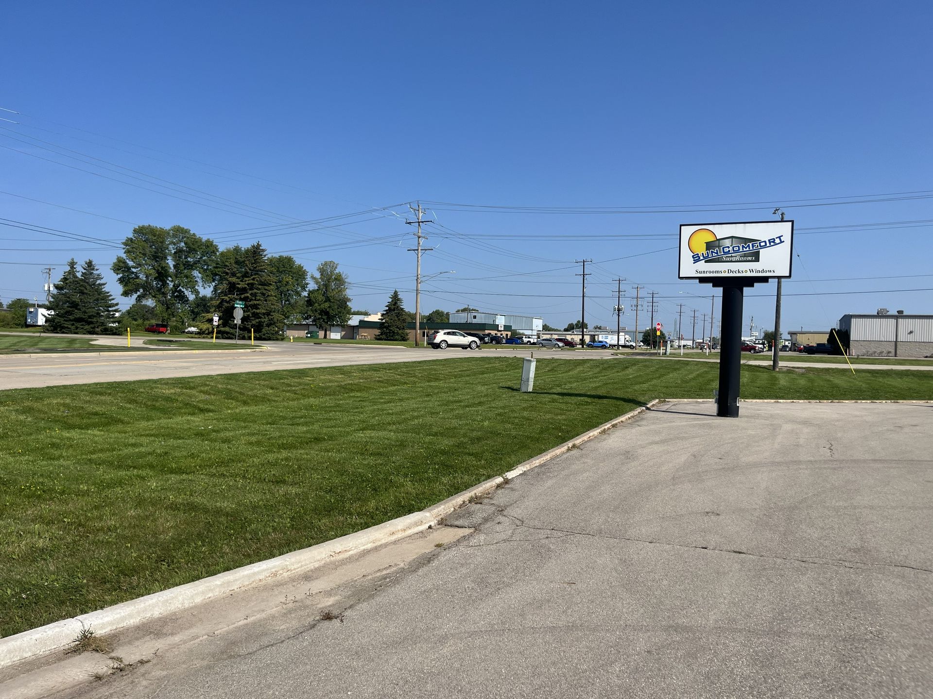 A sign for a car wash on a sunny day. Empty parking lot, green grass, blue sky, power lines.