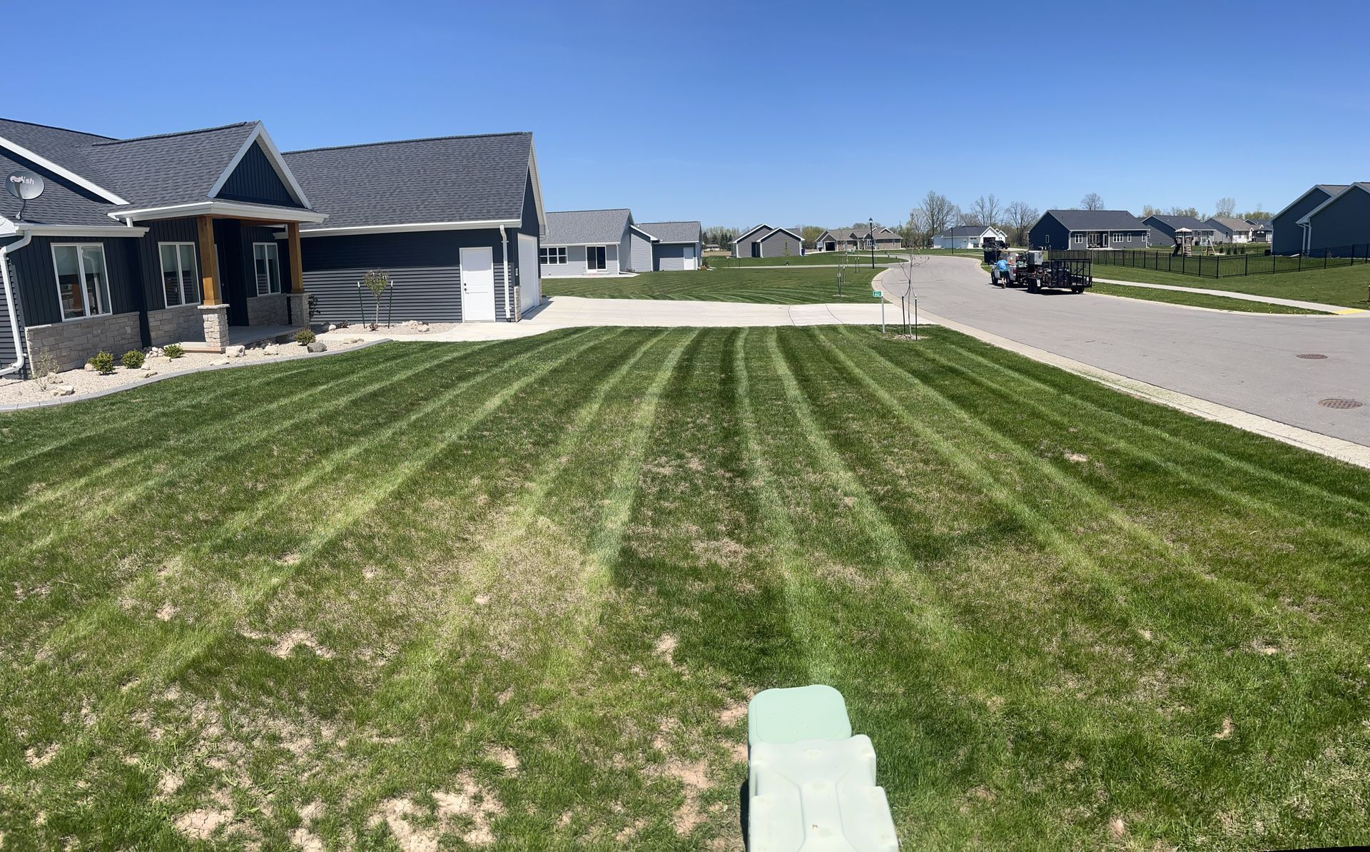Lawn mowed in a new neighborhood with similar houses under a blue sky.