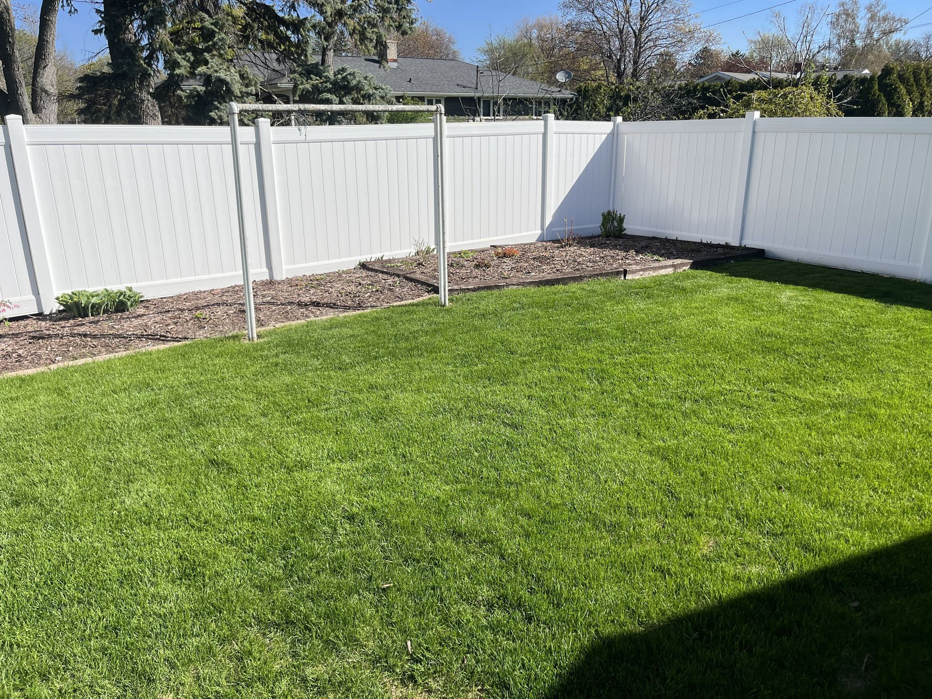 White fenced backyard with green grass and a clothes drying rack.