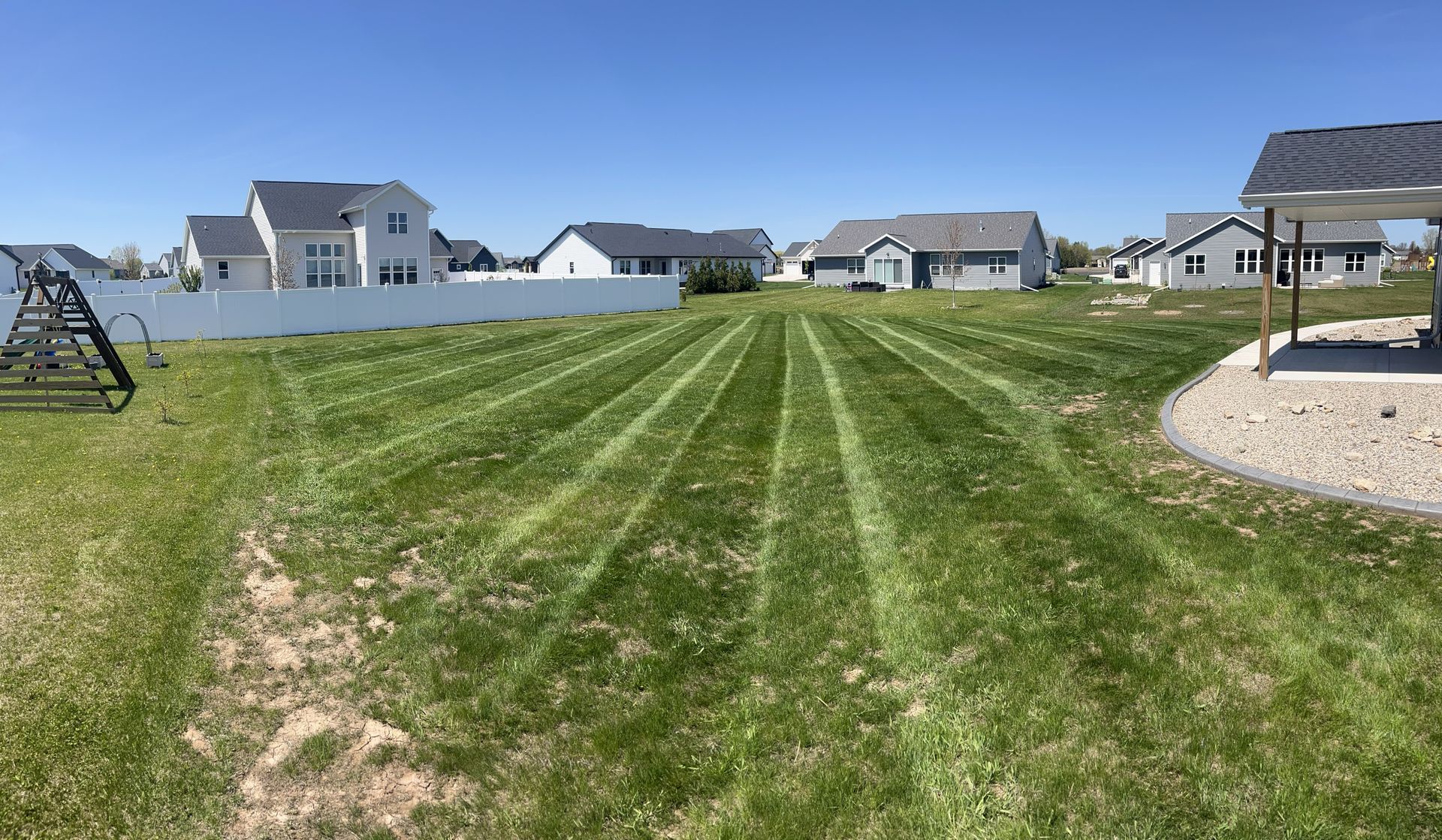 Lawn with freshly cut stripes. Houses and blue sky in background.