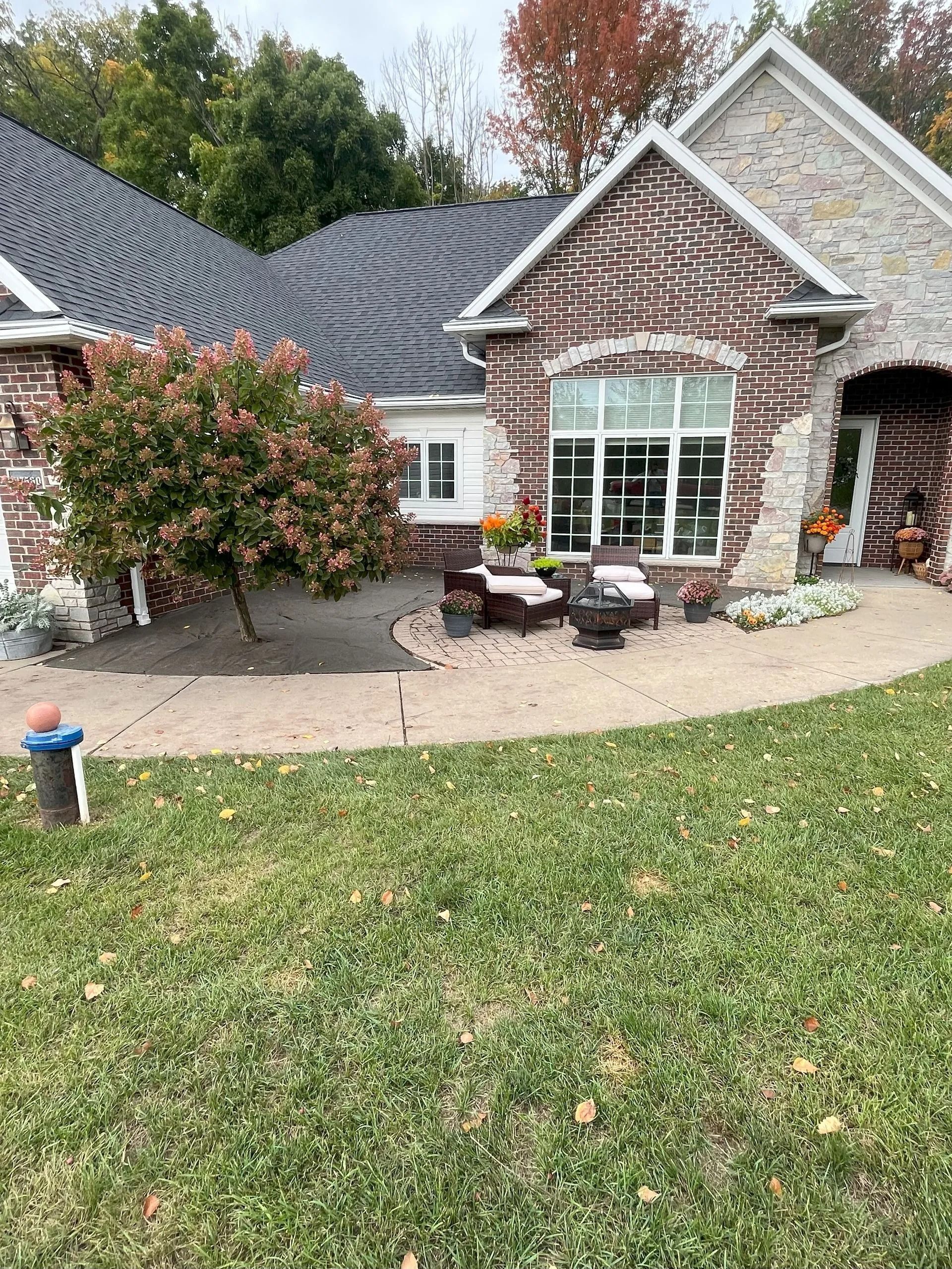 Brick house with a landscaped yard and a circular patio with seating.