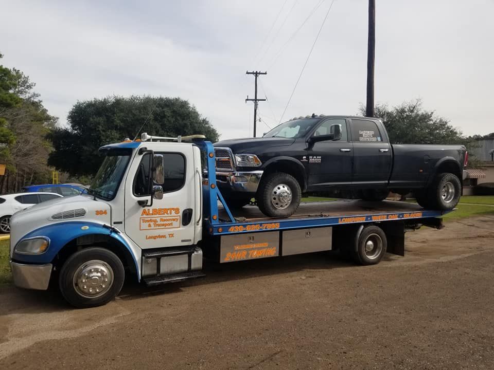 A tow truck with a black pickup truck on its flatbed.