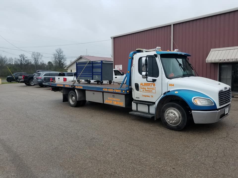 Tow truck parked on an asphalt lot, blue and white cab.