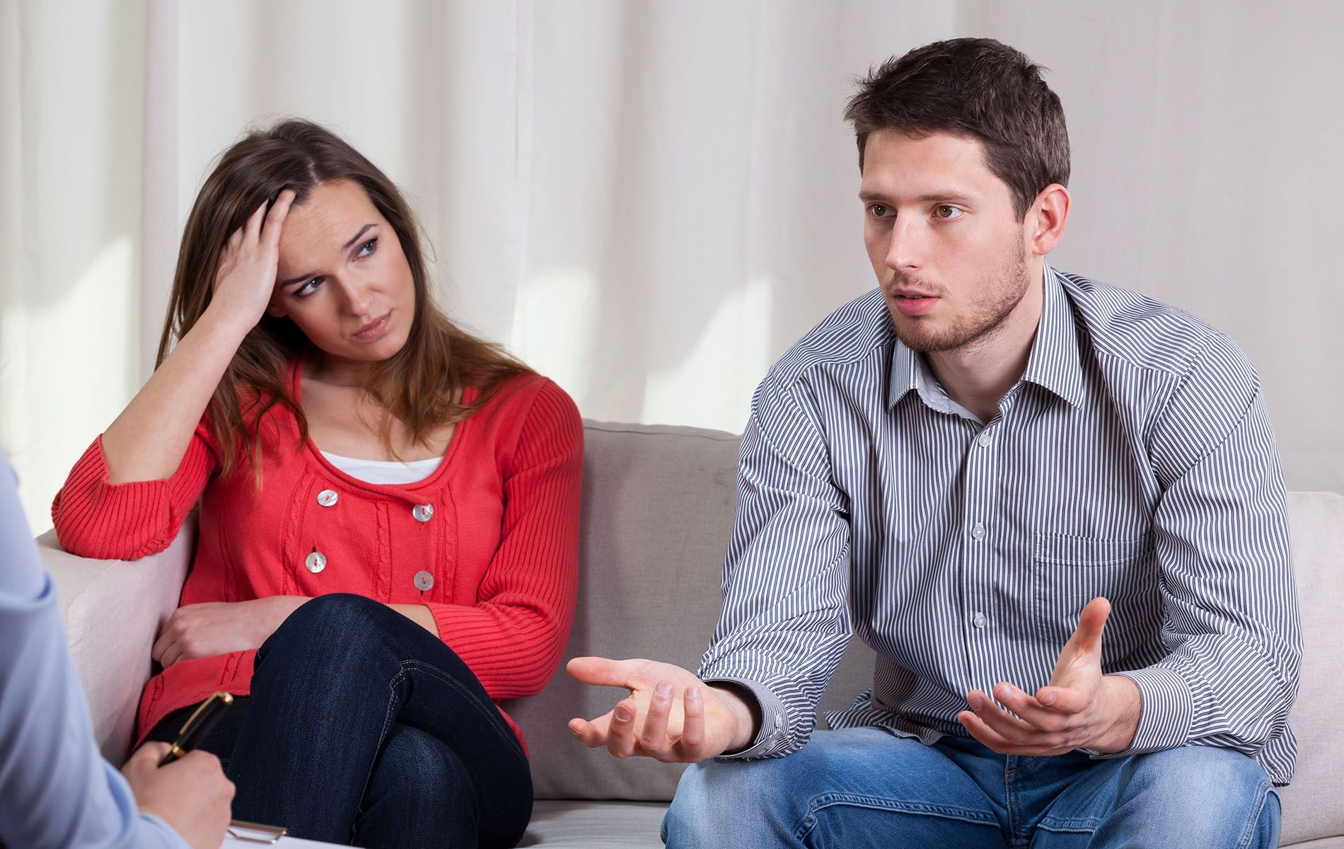 A man and a woman are sitting on a couch having a conversation.