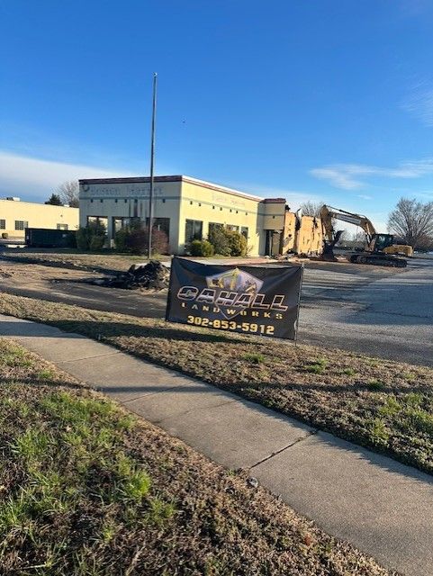 A building is being demolished with a sign in front of it.