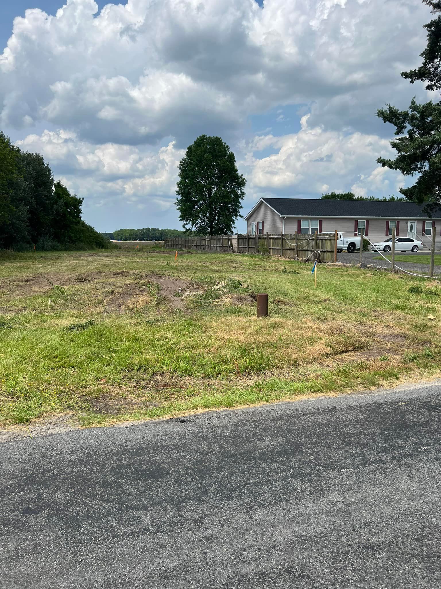 A house is sitting on top of a grassy field next to a road.
