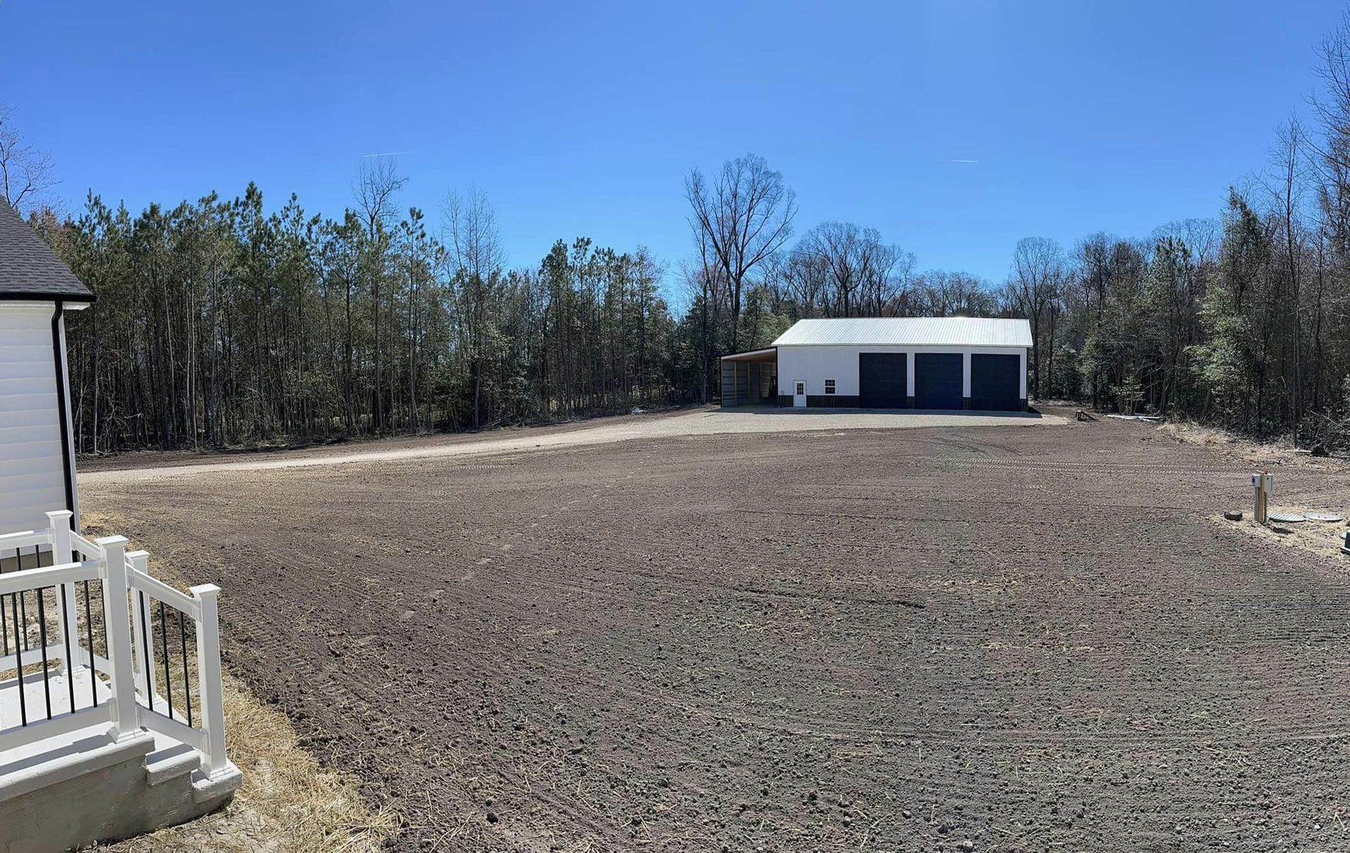 A white house is sitting in the middle of a dirt field.
