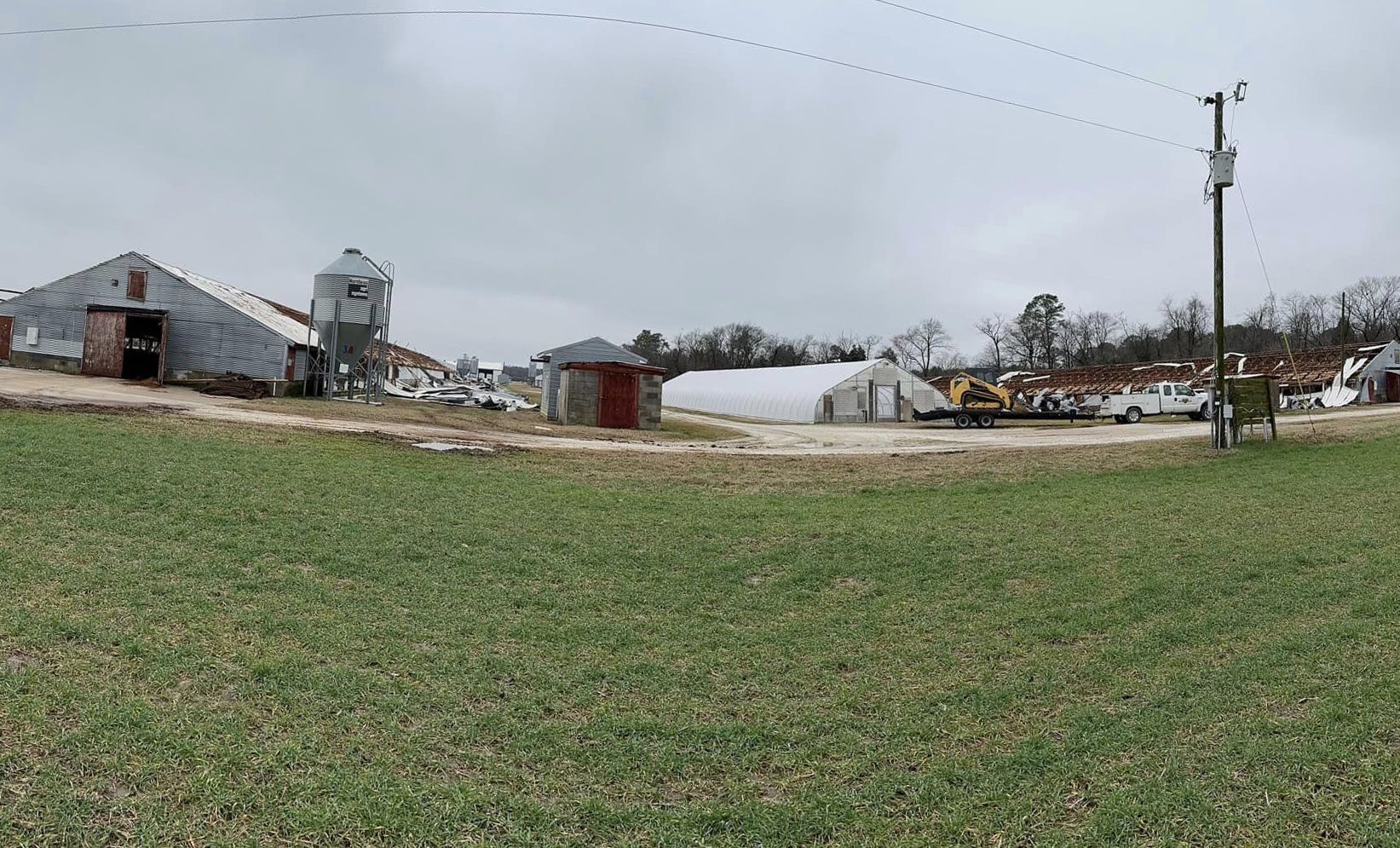 A large grassy field with a lot of buildings in the background.