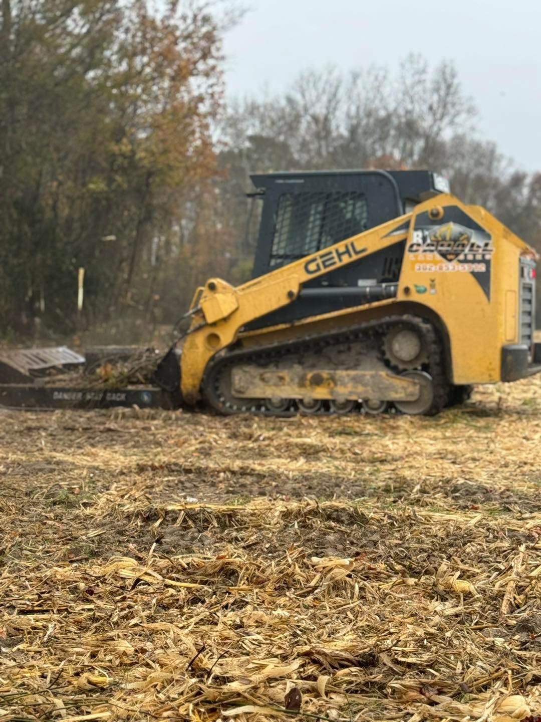 A yellow and black tractor is driving through a field.
