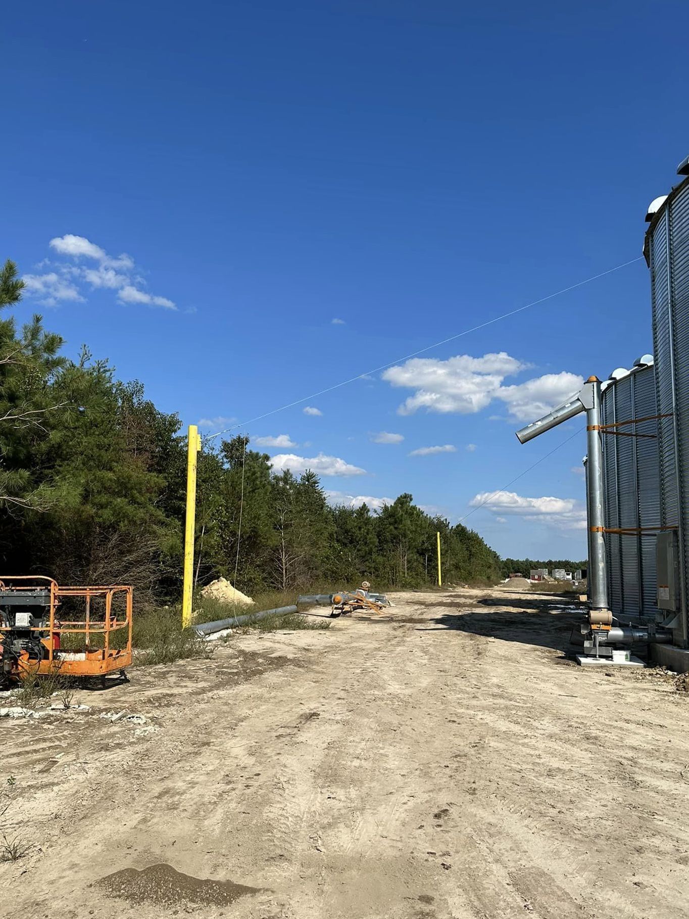 A dirt road leading to a building with a blue sky in the background.