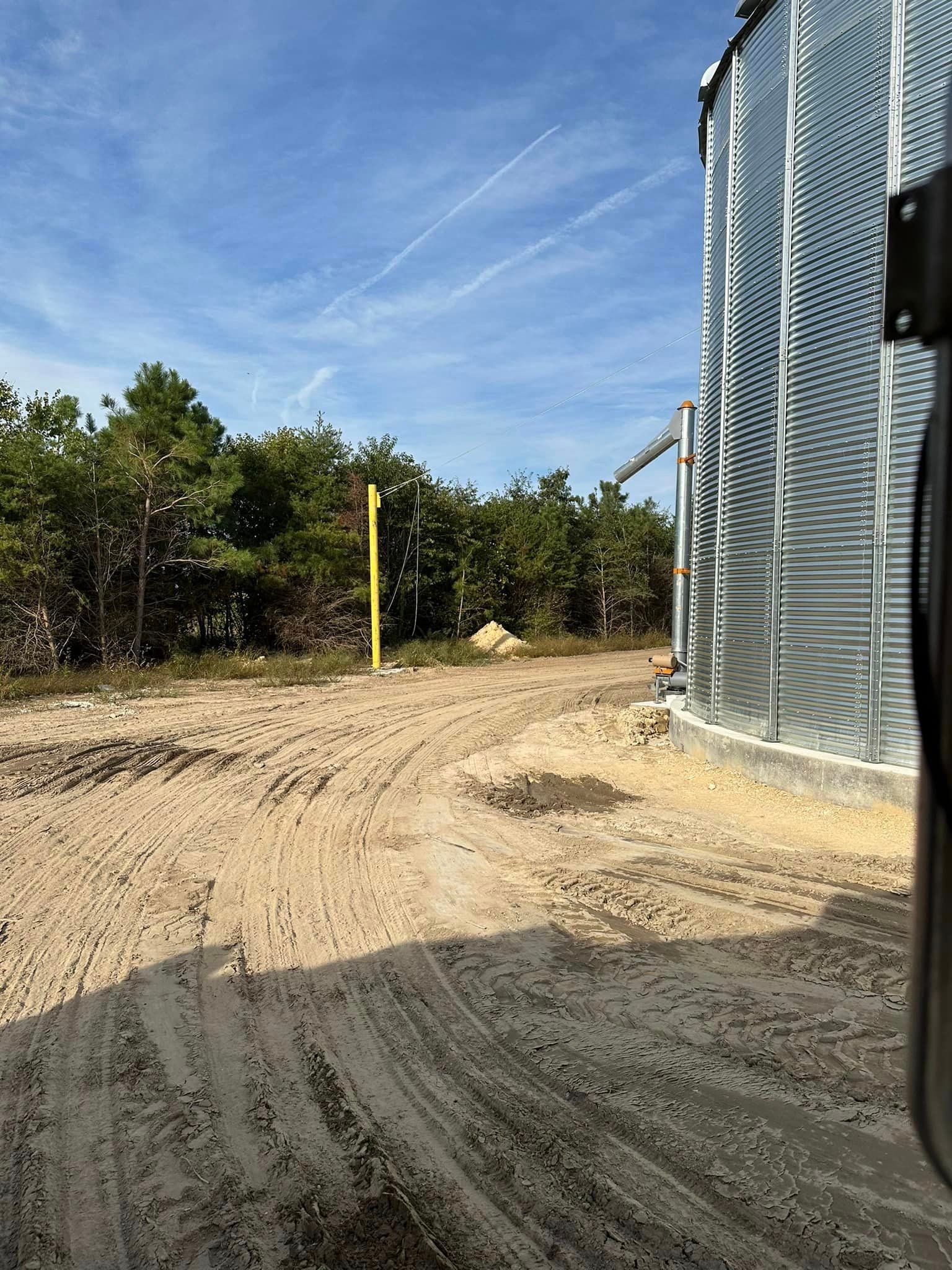 A large metal silo is sitting in the middle of a dirt field.