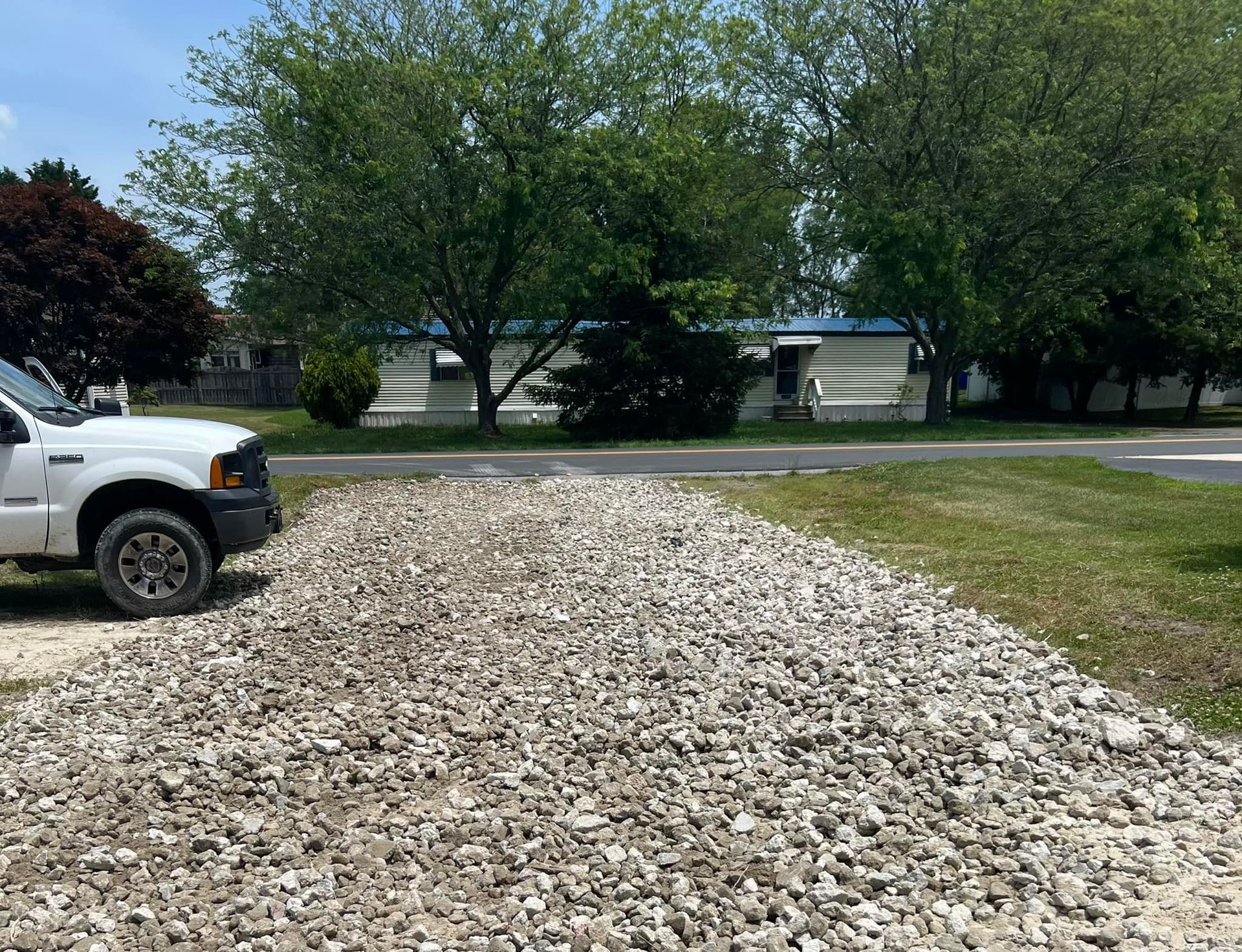 A white truck is parked next to a pile of gravel.