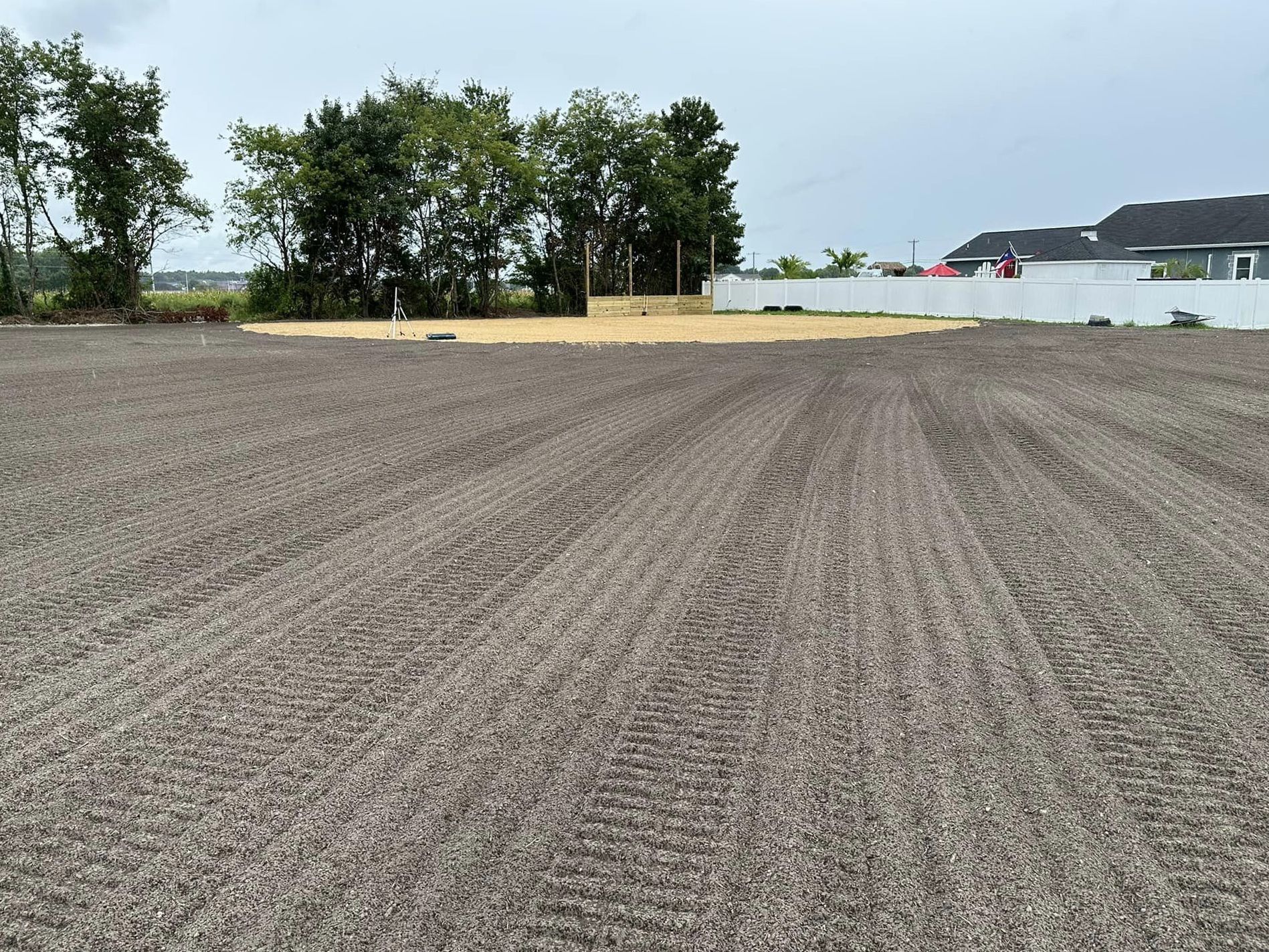 A large dirt field with trees in the background