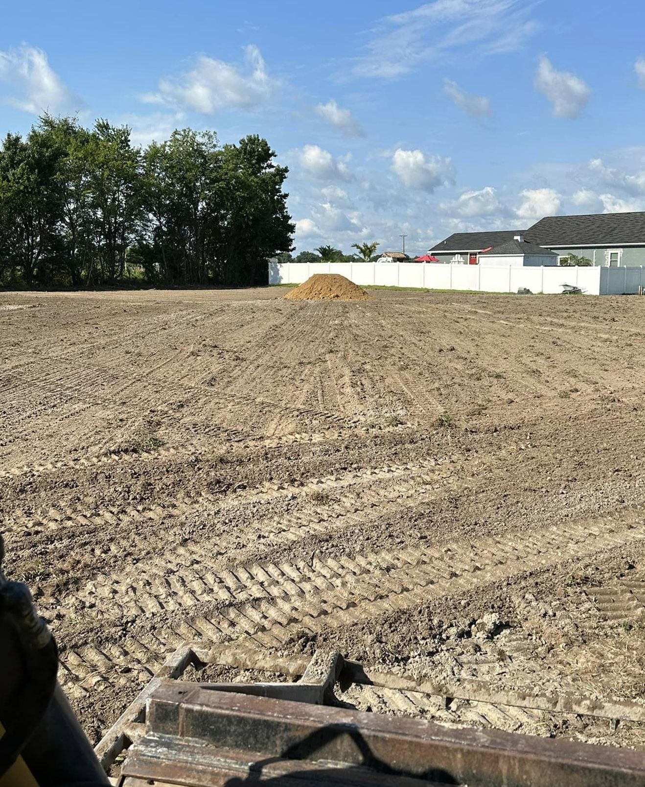 A large dirt field with a house in the background