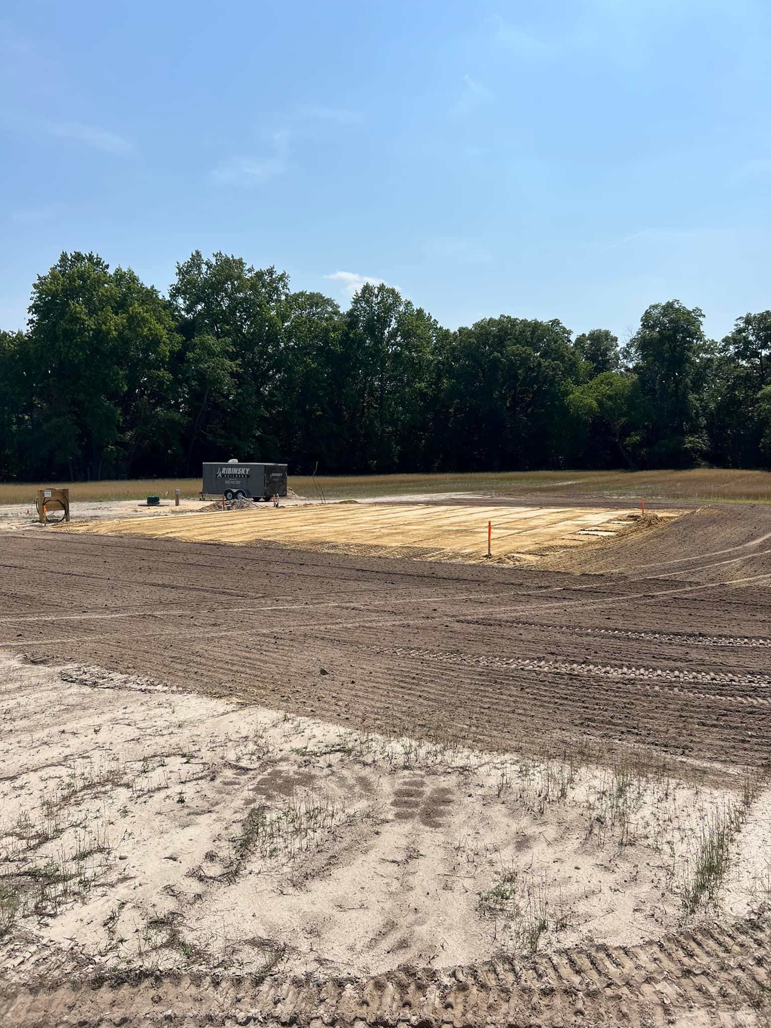 A large dirt field with trees in the background on a sunny day.