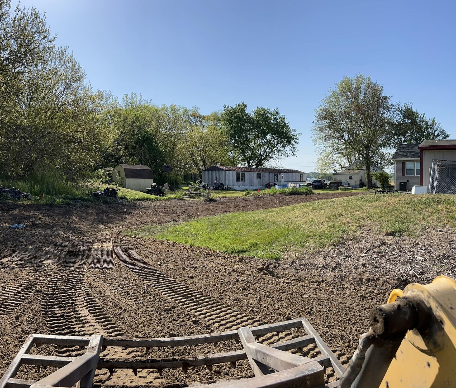 A bulldozer is working on a dirt field in front of a house.