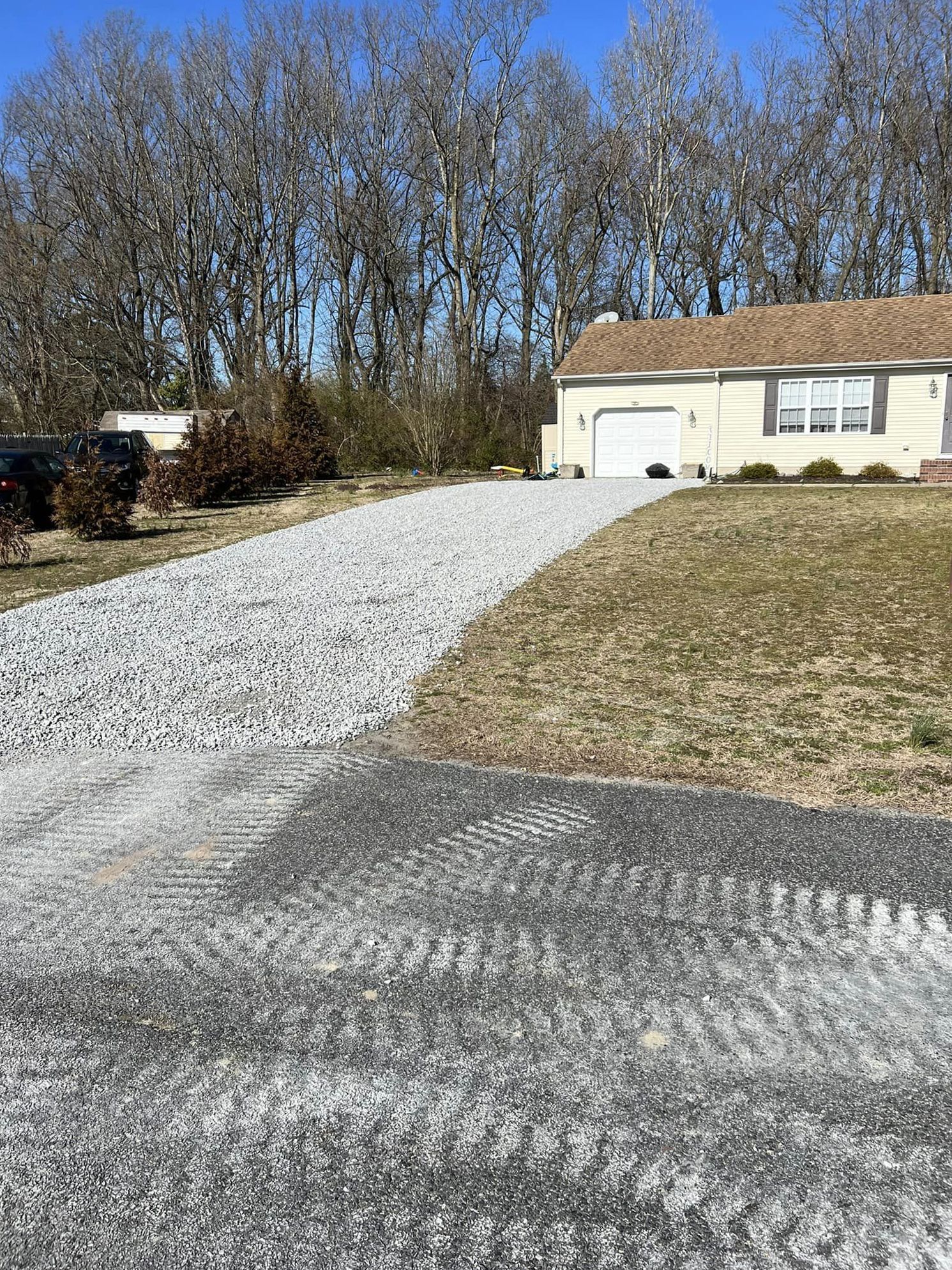 A driveway leading to a house with trees in the background.