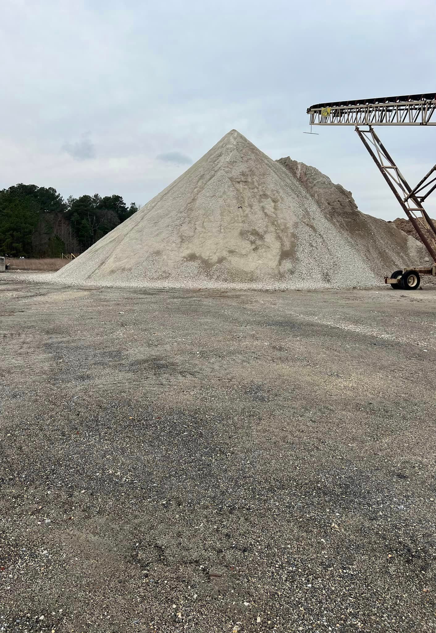 A large pile of gravel is sitting on top of a dirt field.