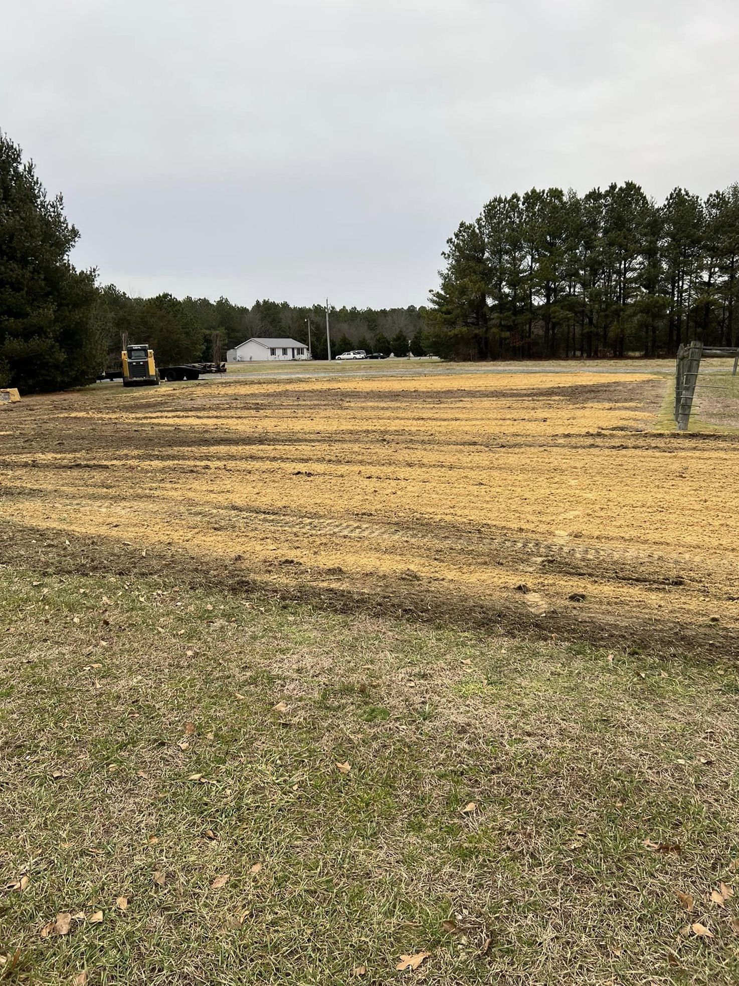 A large field with trees in the background and a house in the background.