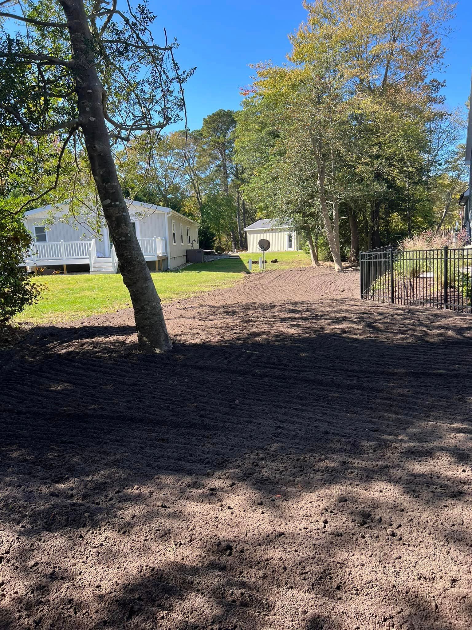 There is a house in the background and a lot of dirt in the foreground.