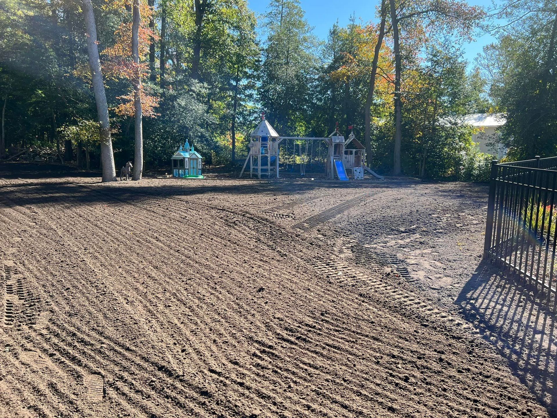 A dirt field with a playground in the background