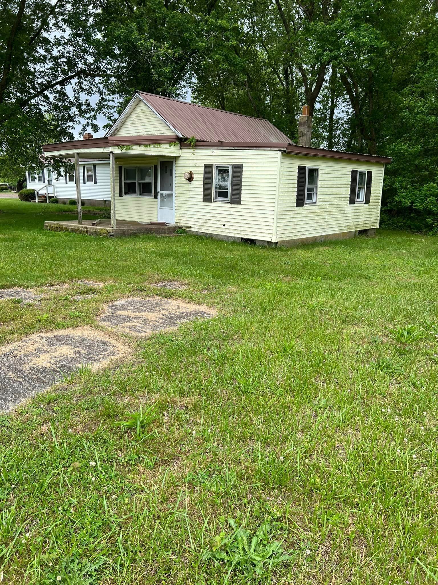 A small white house is sitting in the middle of a lush green field.