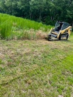 A bulldozer is cutting grass in a field