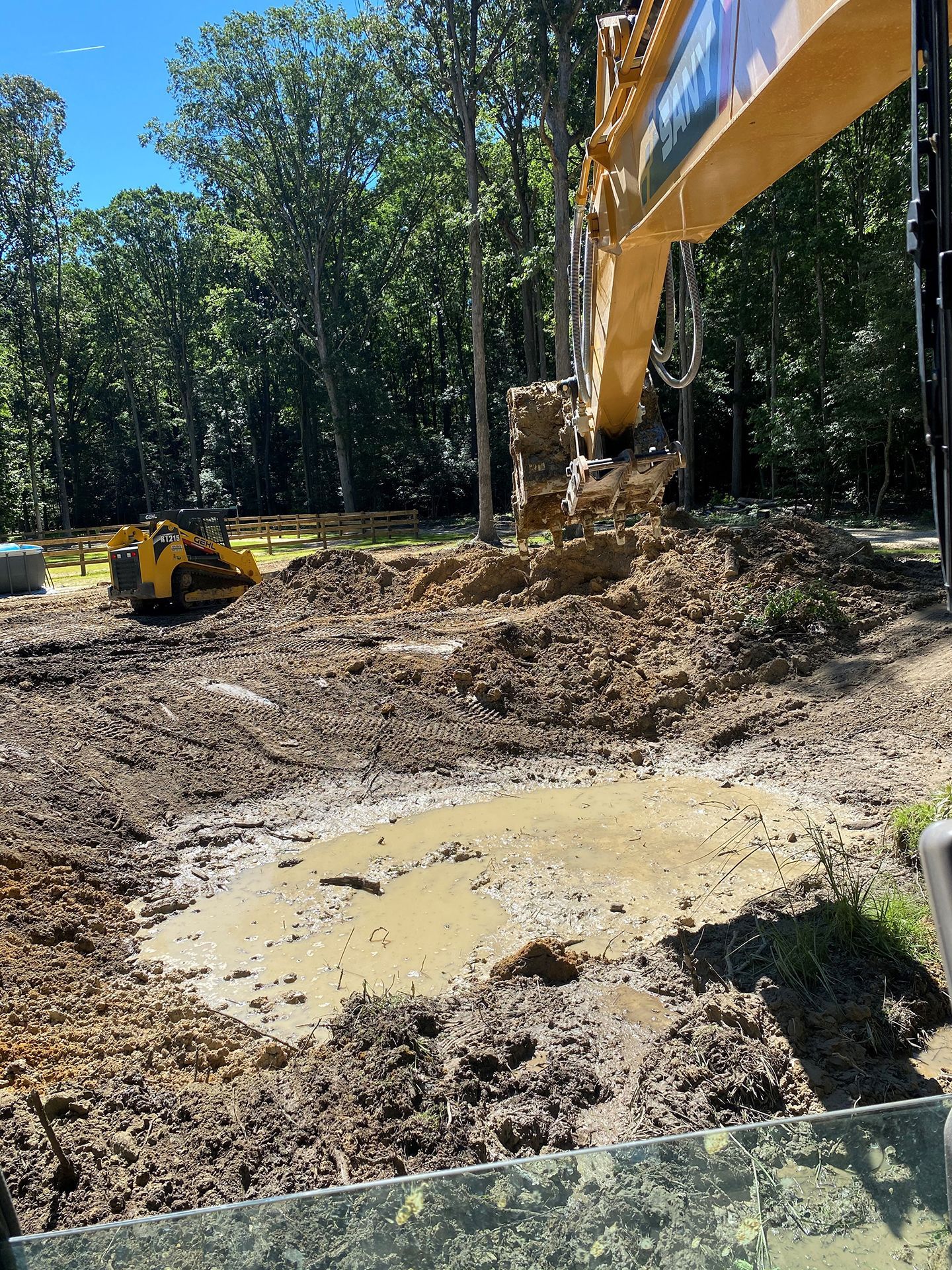 A large yellow excavator is digging a hole in the dirt
