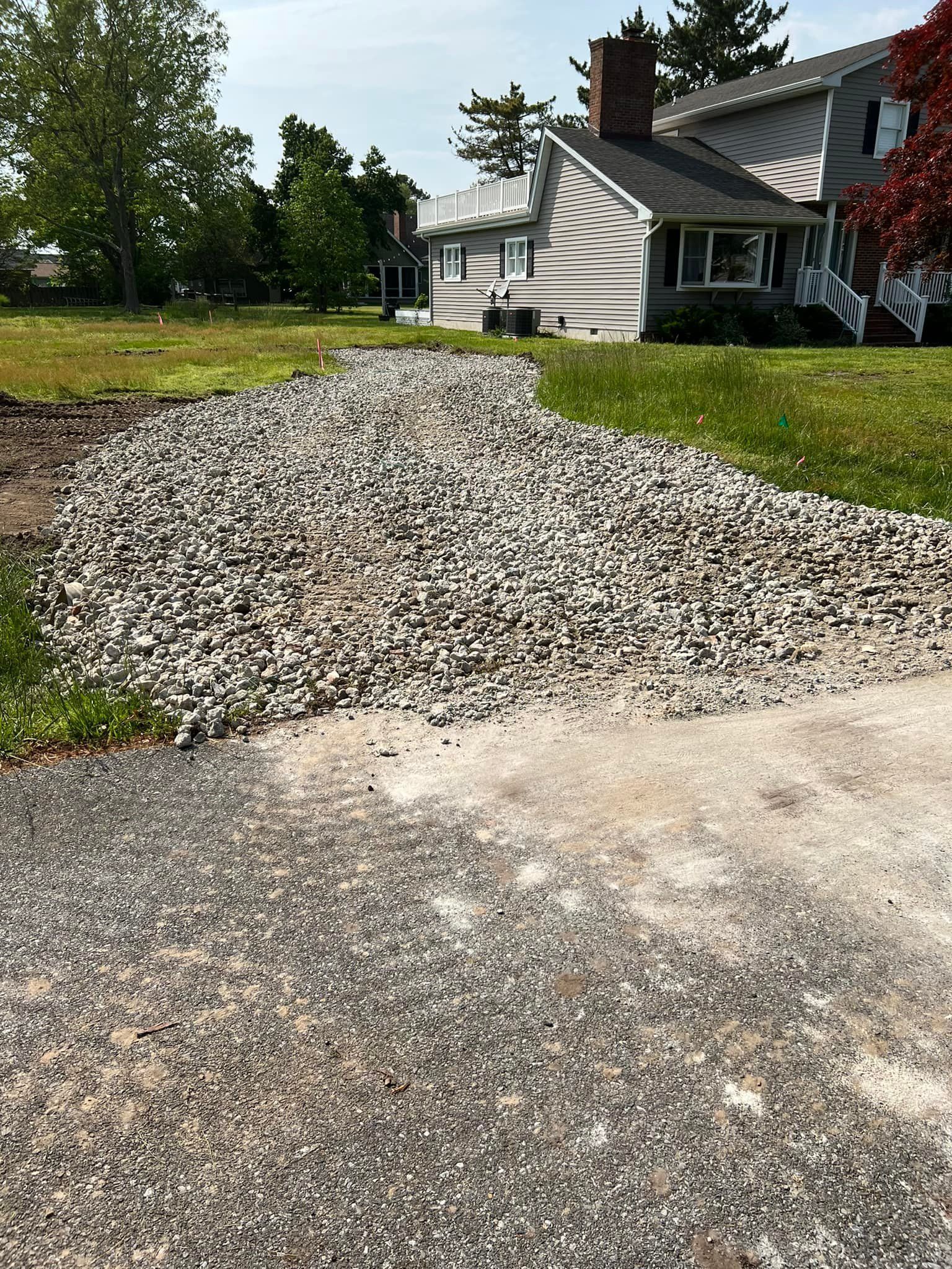 A gravel driveway leading to a house with a house in the background.