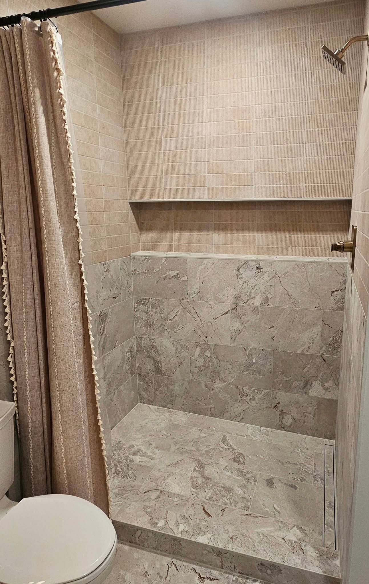 Tiled bathroom with stone shower nook, granite vanity, and beige cabinets and floor tiles