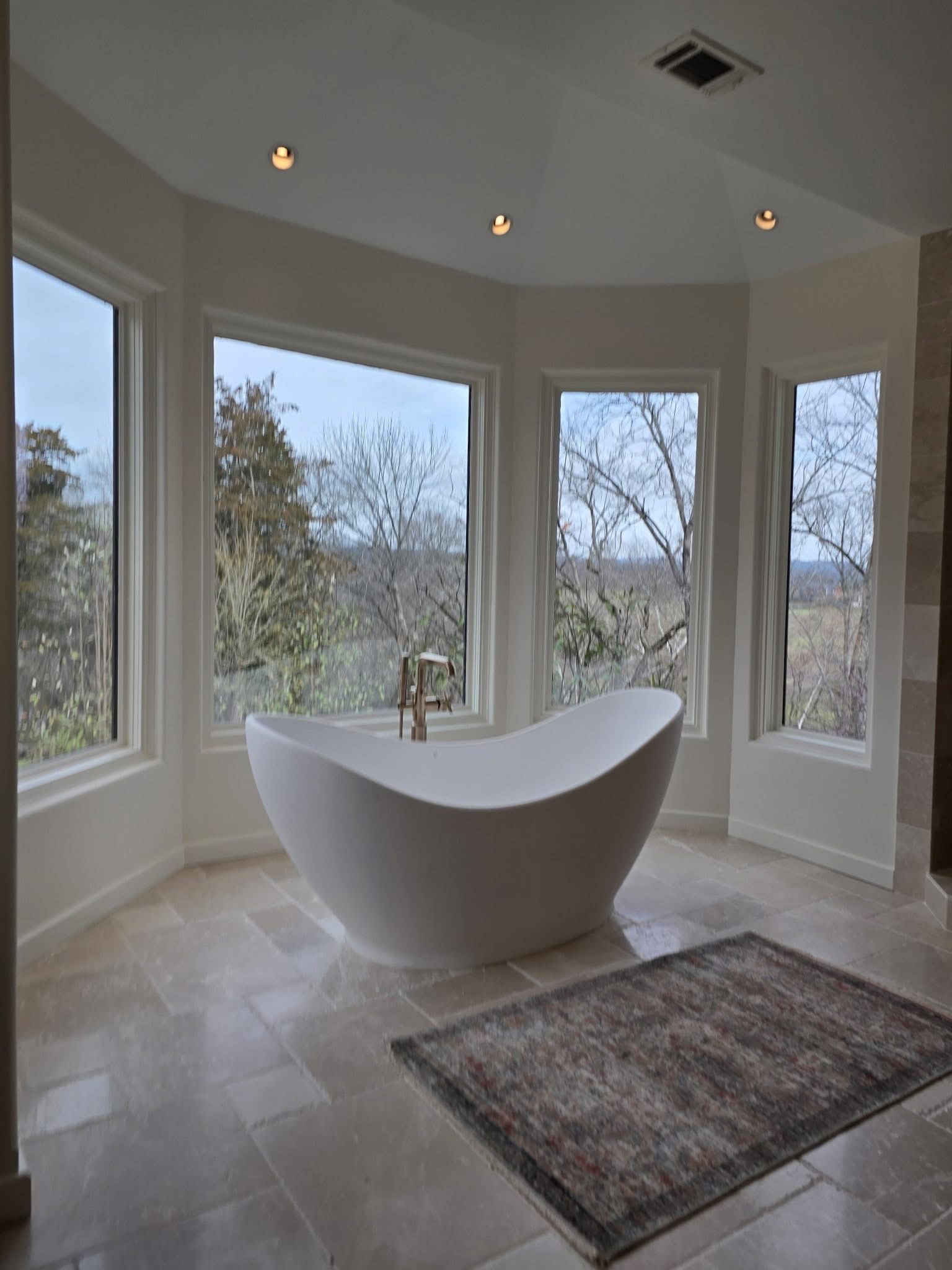 Bright kitchen with gray cabinets, large arched windows, terracotta tile floor, and a wooden island with fruit.